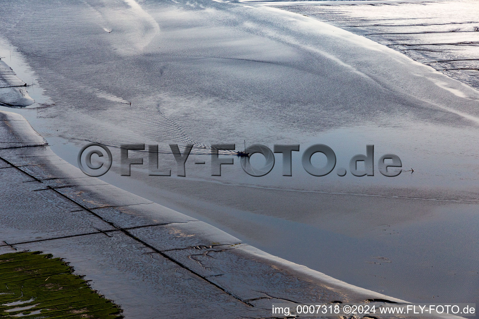 Fishing boat returning home in the evening along the river mouth of Eider into the North Sea in Karolinenkoog in the state Schleswig-Holstein, Germany