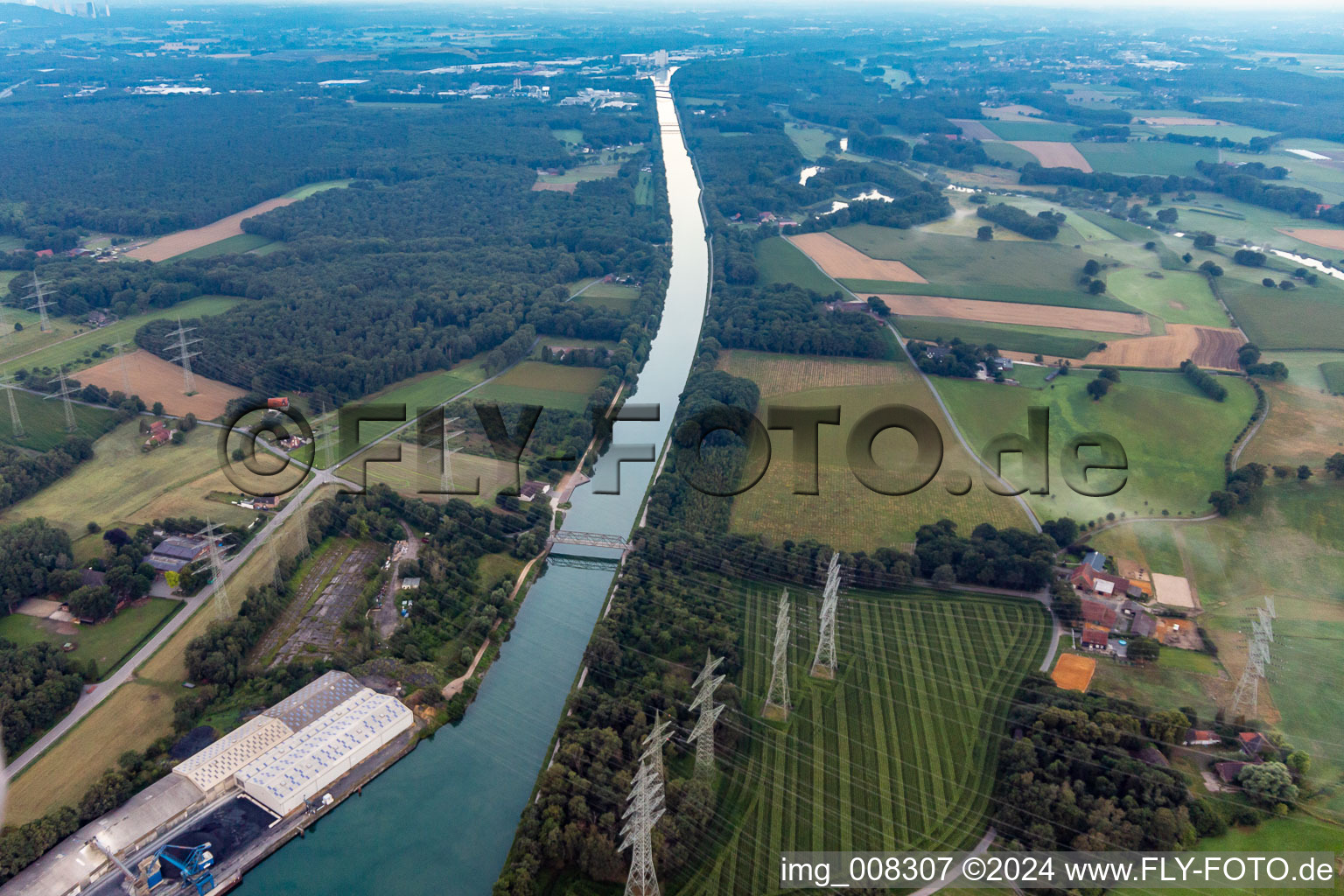 High voltage power lines crossing the channel flow and river banks of the waterway shipping Wesel-Datteln-channel in Marl in the state North Rhine-Westphalia, Germany