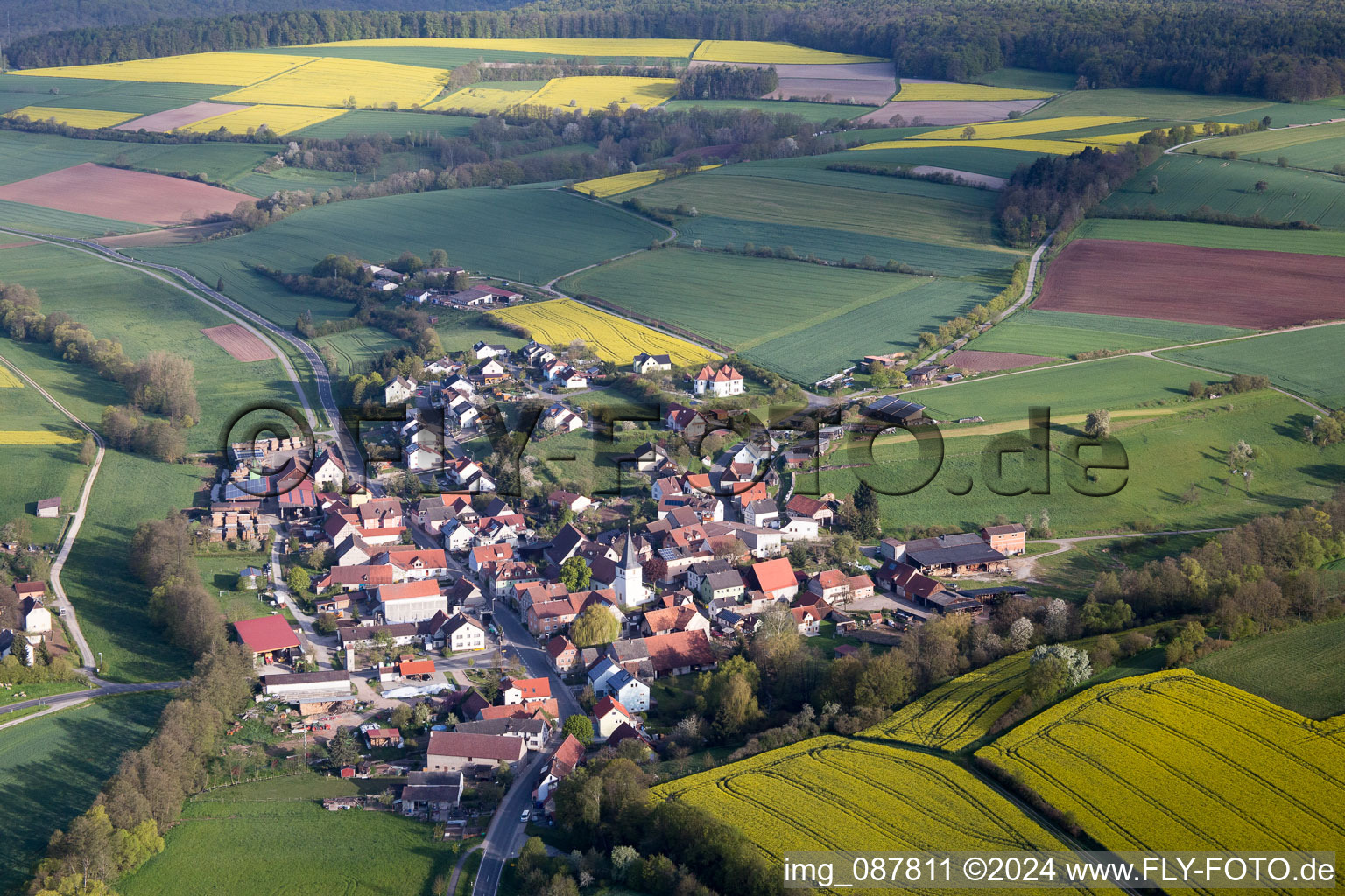 Aerial view of Village - view on the edge of agricultural fields and farmland in the district Falsbrunn in Rauhenebrach in the state Bavaria, Germany