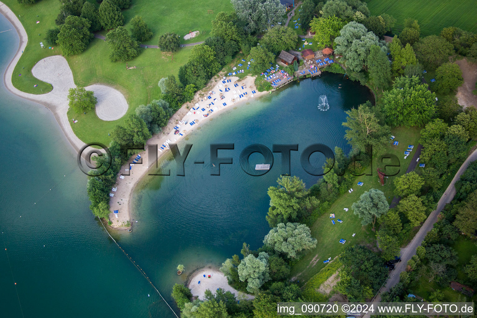 Bathers on the lawn and in the the pool of the nautral lake of the MIRAMAR Erlebnisbad in Weinheim in the state Baden-Wurttemberg