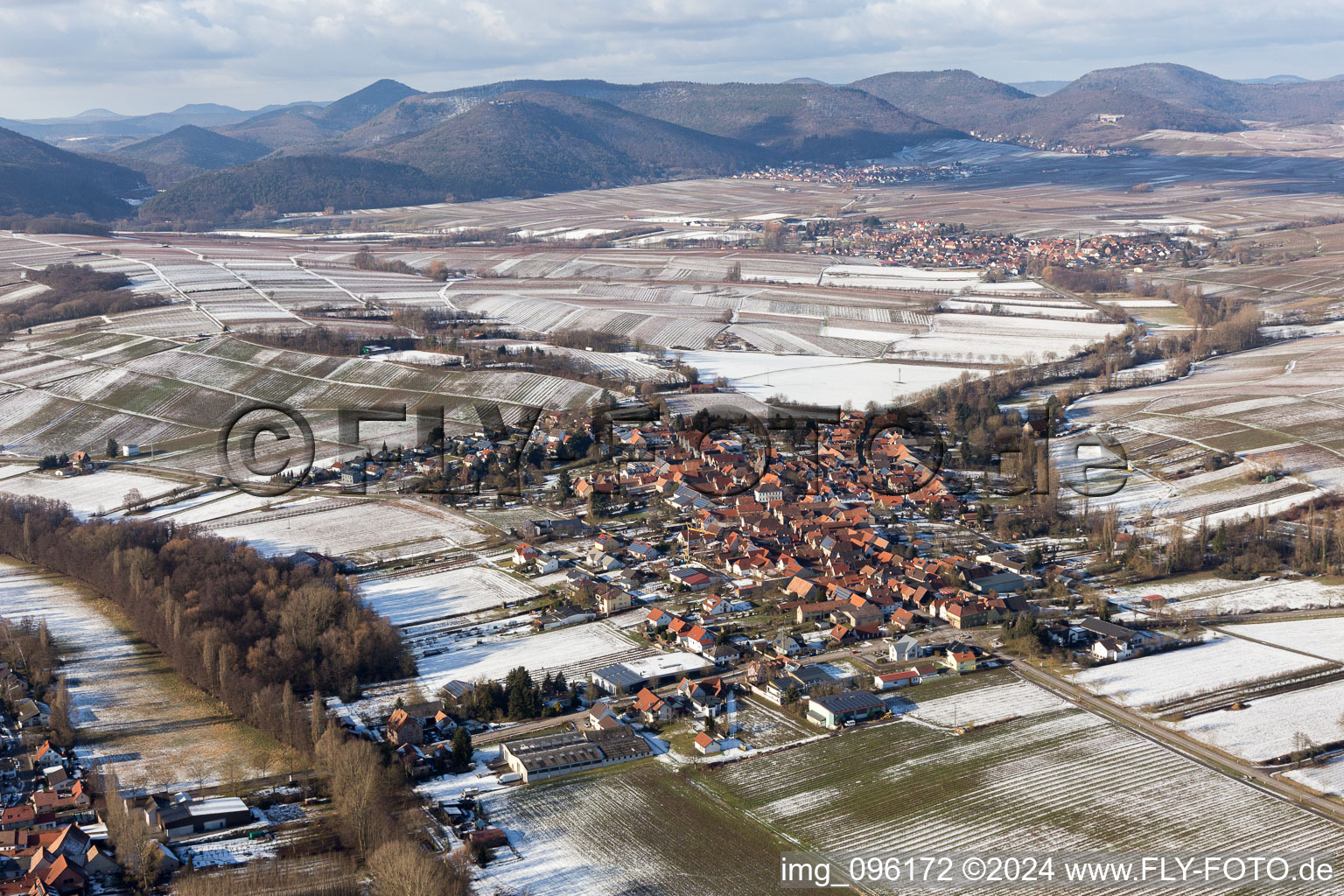 Aerial view of Wintry snowy Village - view on the edge of agricultural fields and farmland in the district Heuchelheim in Heuchelheim-Klingen in the state Rhineland-Palatinate, Germany