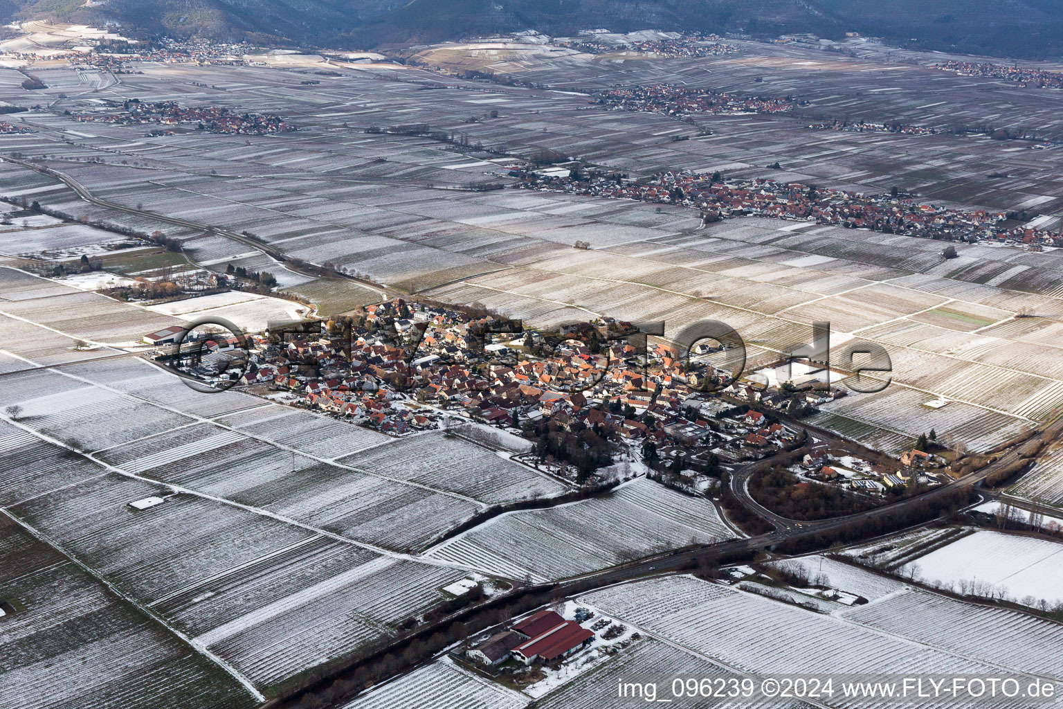 Aerial view of Wintry snowy Village - view on the edge of agricultural fields and farmland in Walsheim in the state Rhineland-Palatinate, Germany