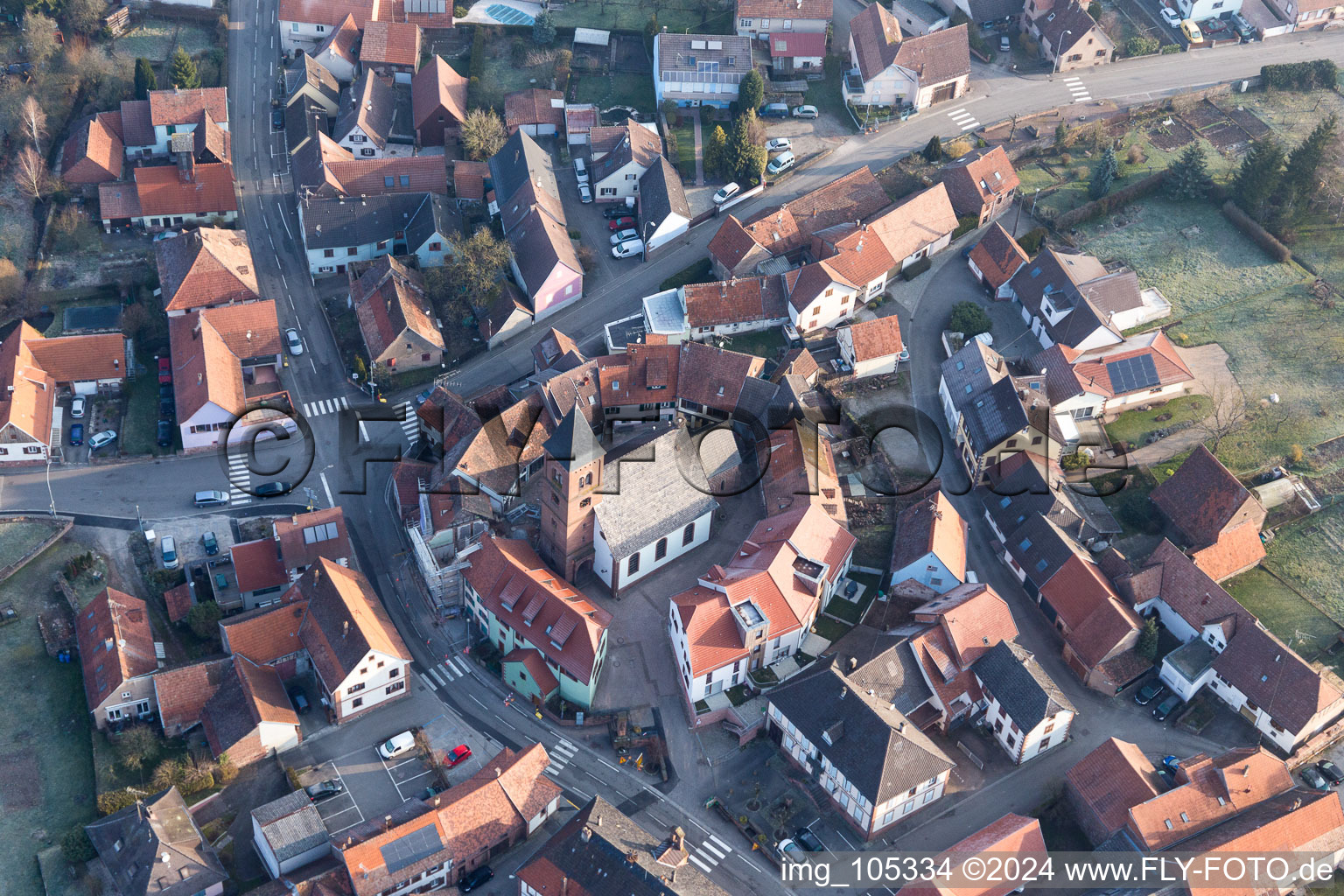 Protestantic Church building in the center of a circle of houses in the village of in Dossenheim-sur-Zinsel in Grand Est, France from the drone perspective