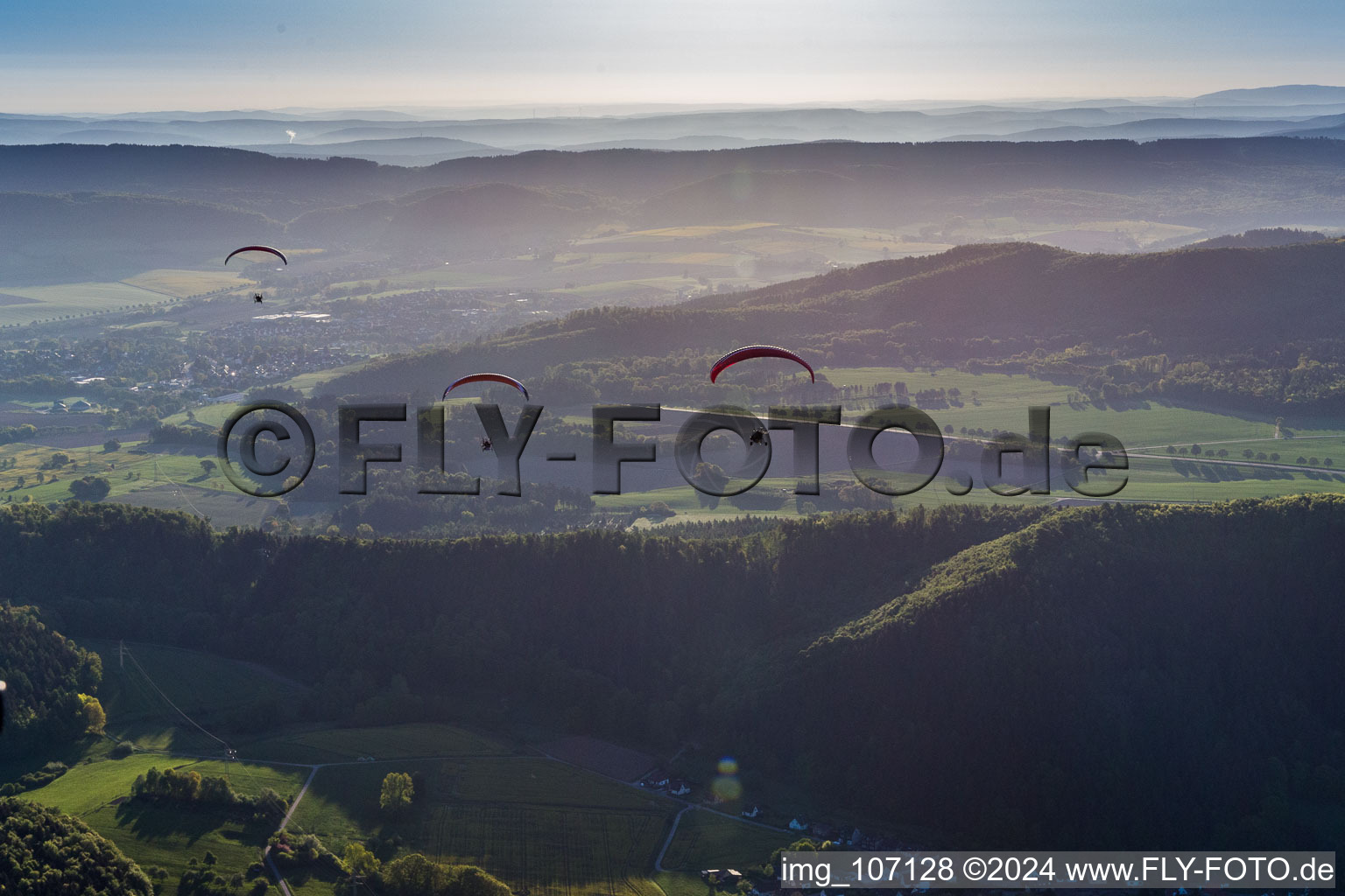 Forest and mountain scenery with 3 Paragleitern in Weserbergland in Holenberg in the state Lower Saxony, Germany