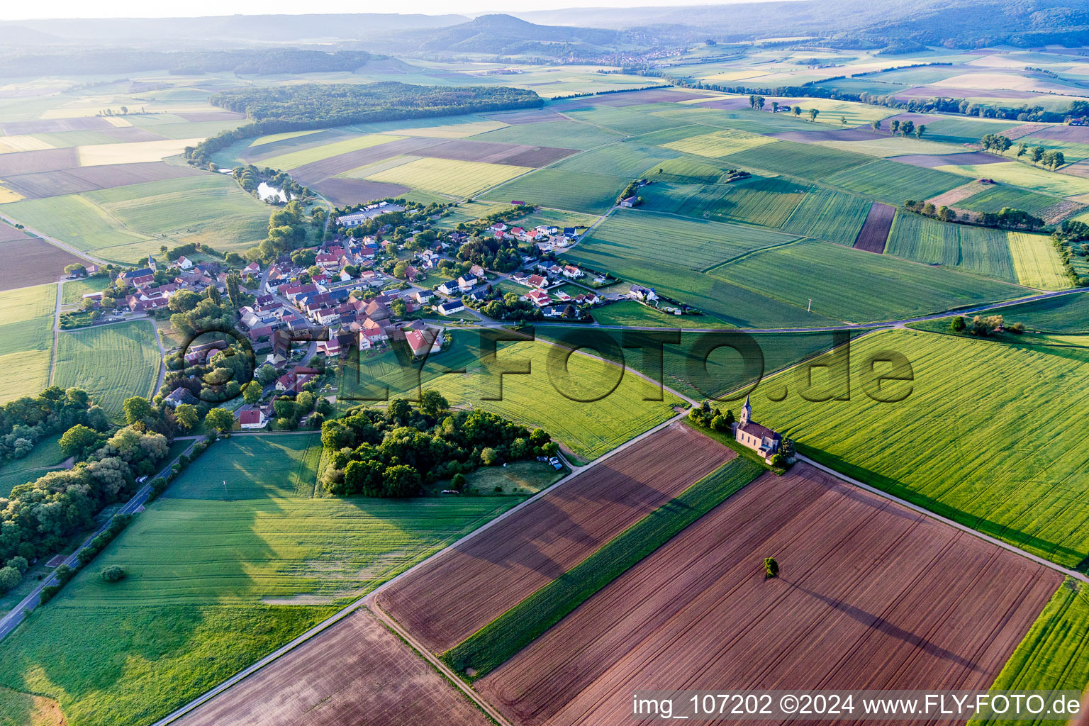 Agricultural land and field borders surround the settlement area of the village in Dingolshausen in the state Bavaria, Germany