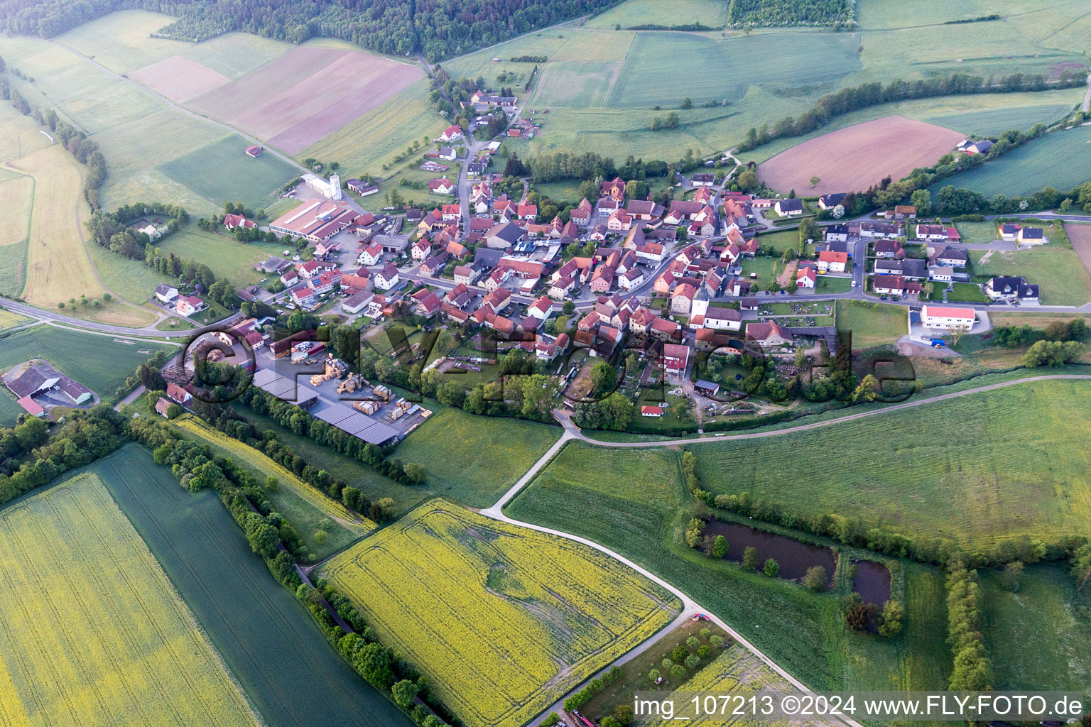 Oblique view of Agricultural land and field borders surround the settlement area of the village in Wustviel in the state Bavaria, Germany