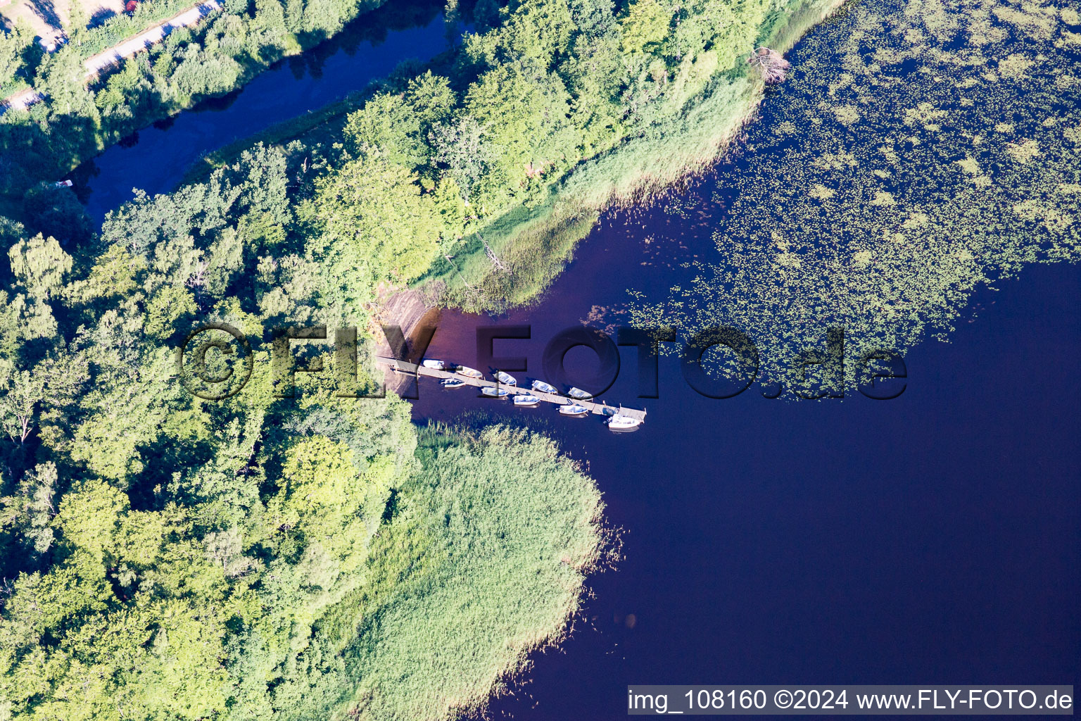 Riparian areas on the swamp coloured (Smaland) lake Asnen with water lillys, boat bridge, and swimming beach in Torne in Kronobergs laen, Sweden