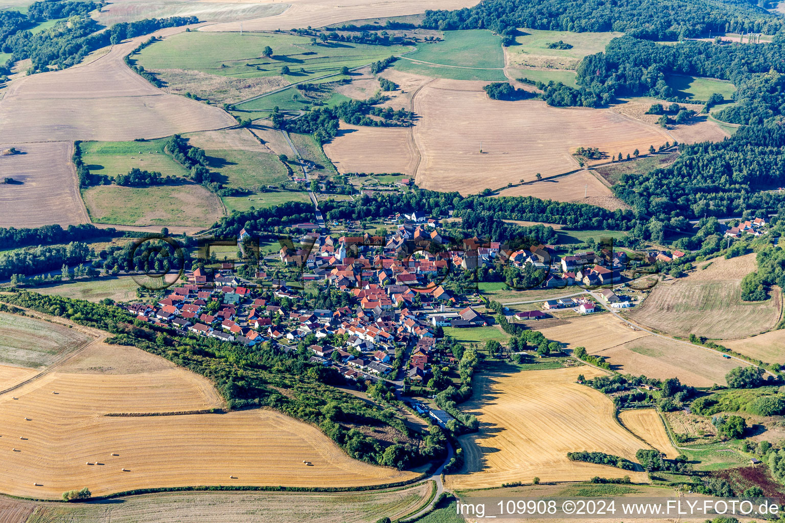 Agricultural land and field borders surround the settlement area of the village in Niedermoschel in the state Rhineland-Palatinate, Germany