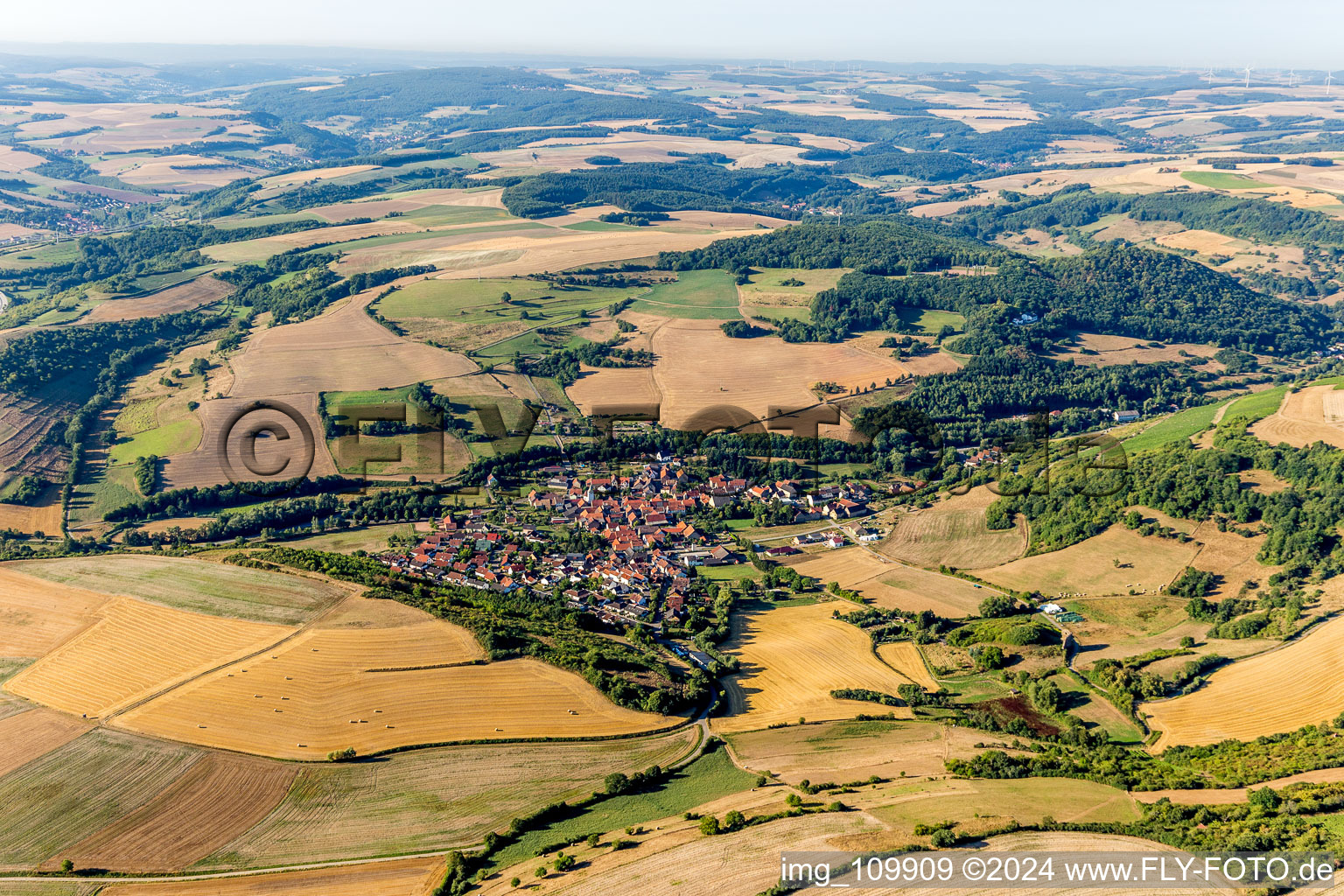 Aerial view of Agricultural land and field borders surround the settlement area of the village in Niedermoschel in the state Rhineland-Palatinate, Germany