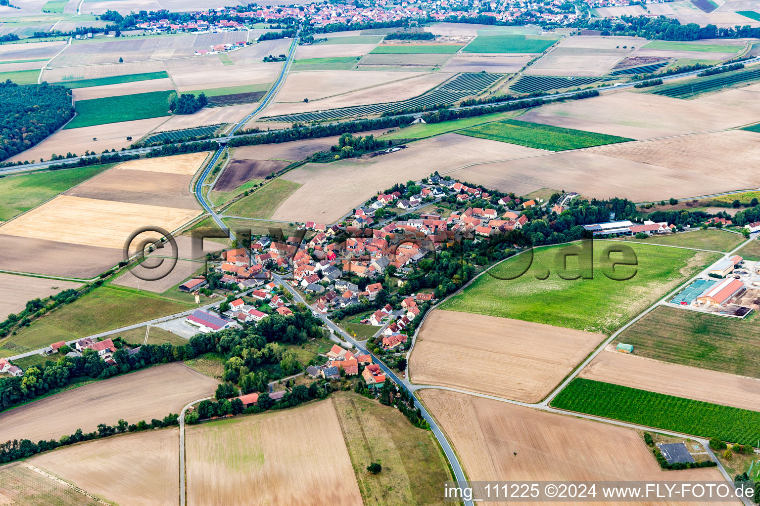 Aerial view of Agricultural land and field borders surround the settlement area of the village in Feuerbach in the state Bavaria, Germany