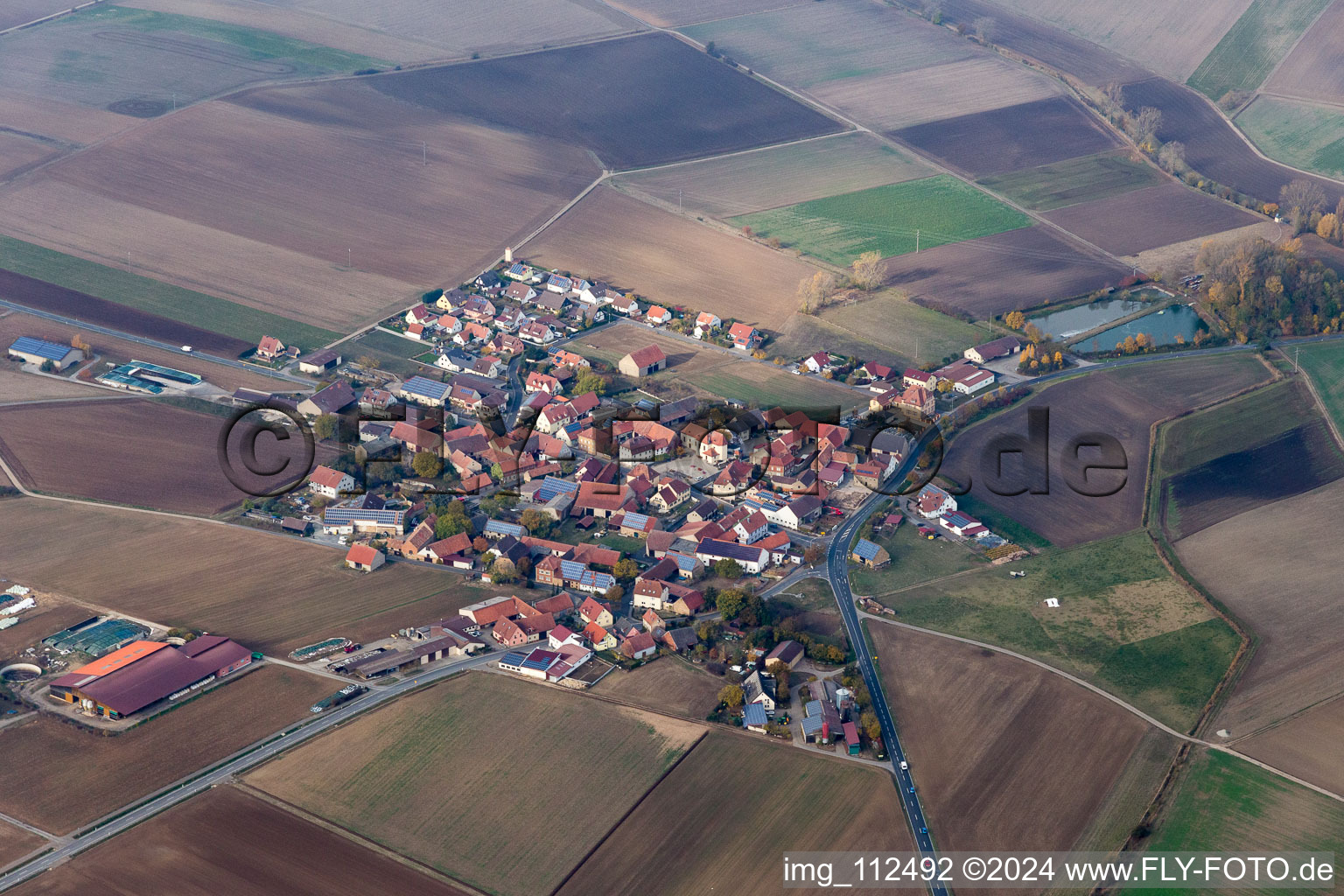 Aerial view of Agricultural land and field borders surround the settlement area of the village in Frankenwinheim in the state Bavaria, Germany