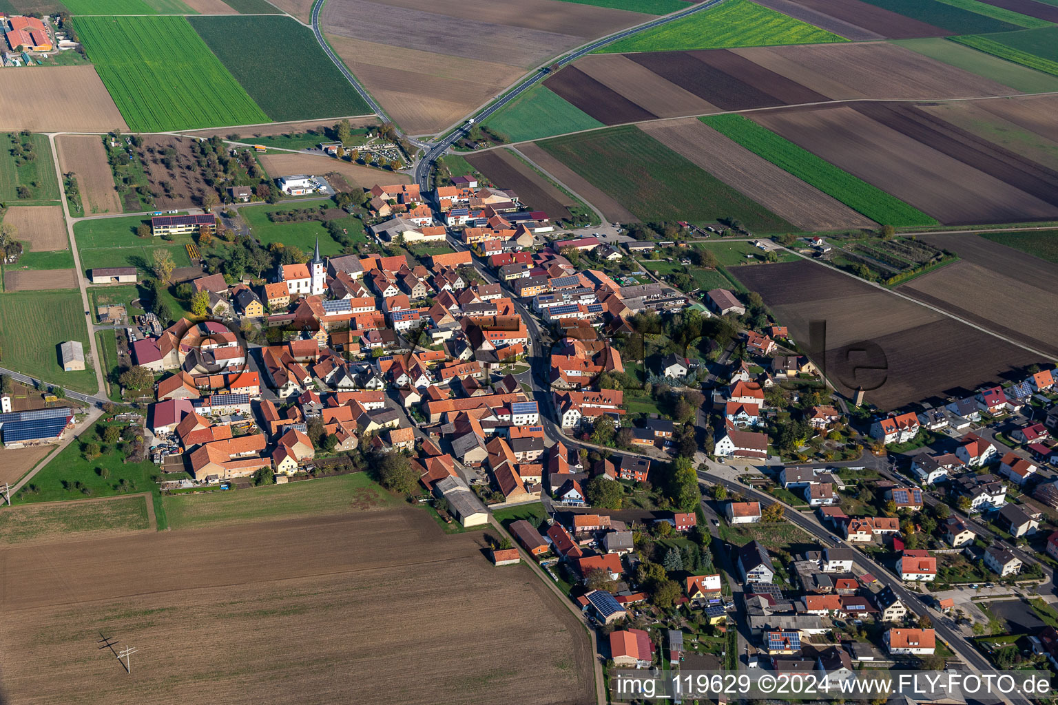 Agricultural land and field borders surround the settlement area of the village in Kolitzheim in the state Bavaria, Germany from above