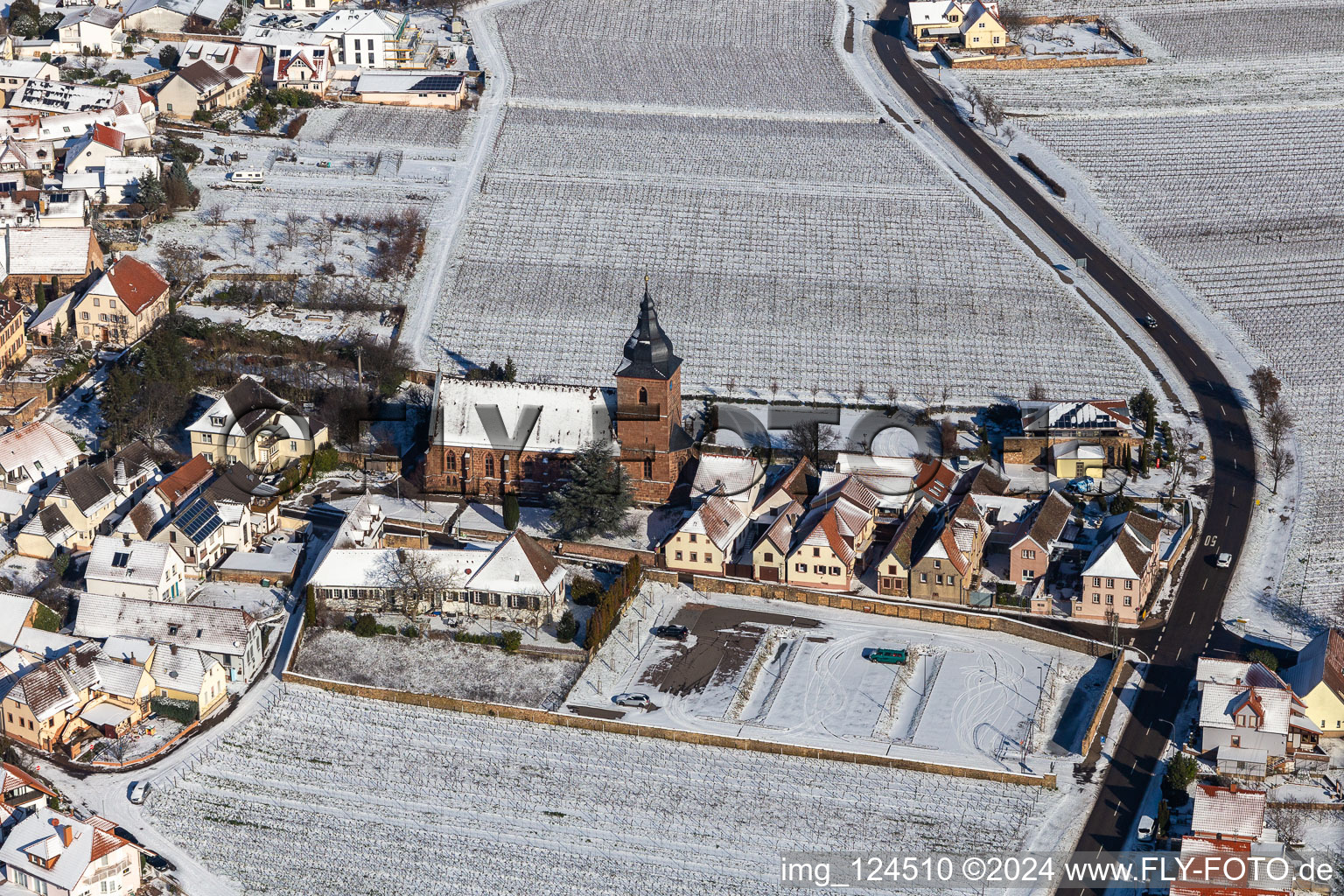 Wintry snowy church building of Catholic parish church of the Visitation of Mary, the wine house Vinothek Messmer, Ritterhof zur Rose in Burrweiler in the state Rhineland-Palatinate, Germany