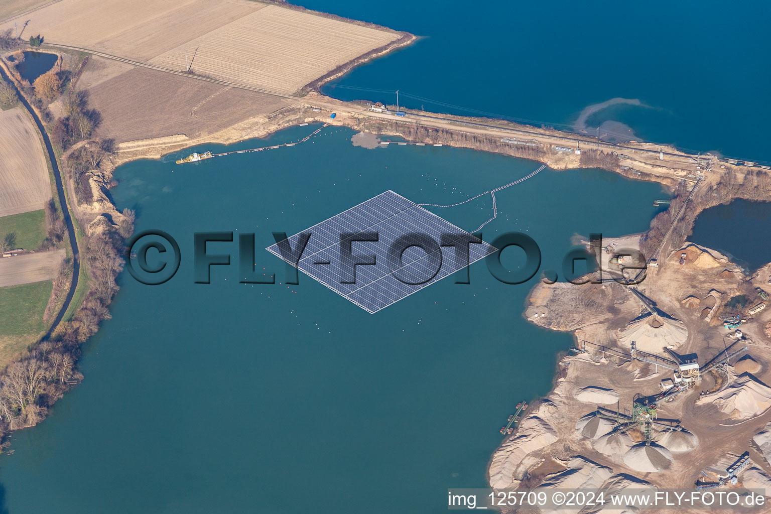 Floating solar power plant and panels of photovoltaic systems on the surface of the water on a quarry pond for gravel extraction in Leimersheim in the state Rhineland-Palatinate, Germany