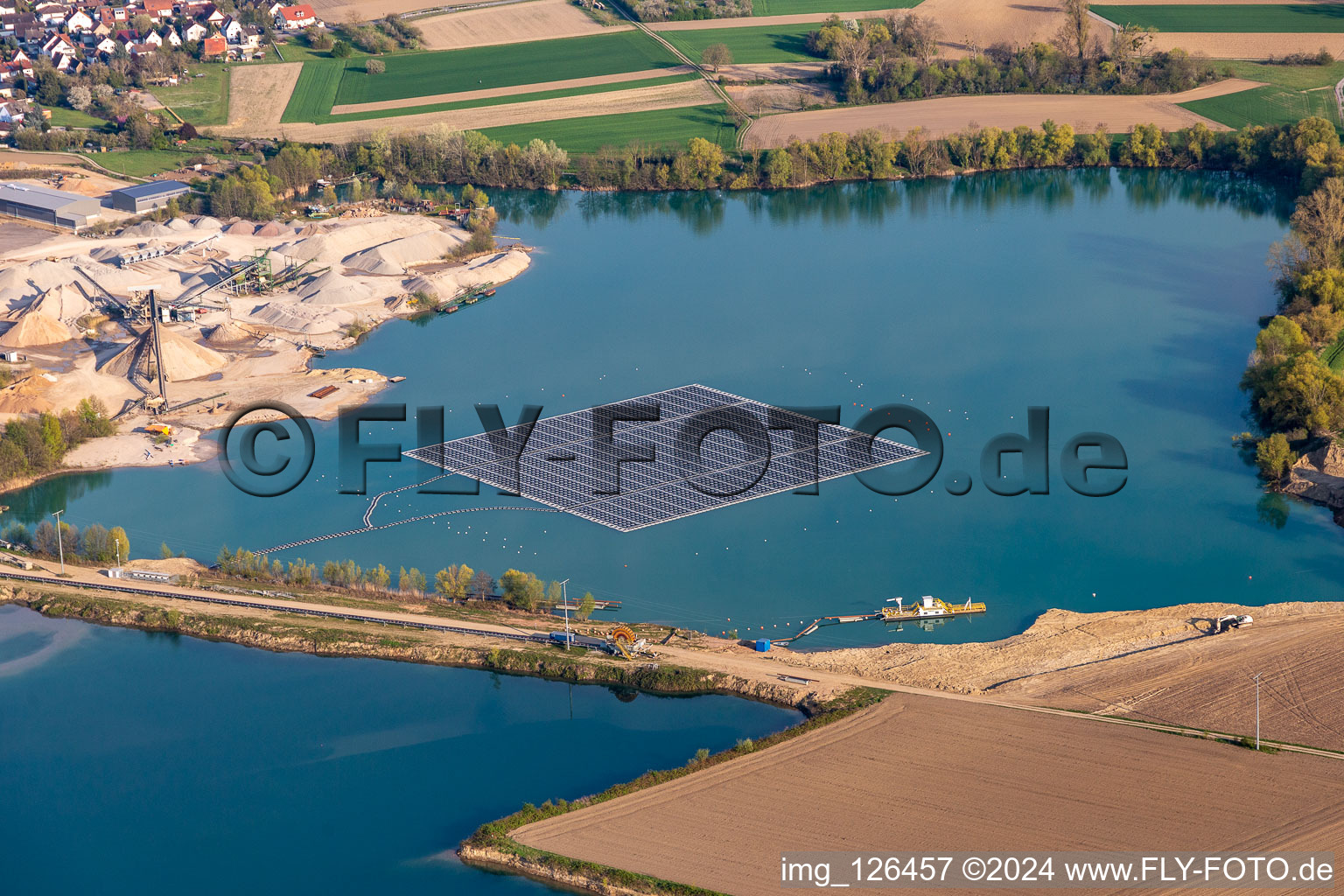 Aerial view of Floating solar power plant and panels of photovoltaic systems on the surface of the water on a quarry pond for gravel extraction in Leimersheim in the state Rhineland-Palatinate, Germany