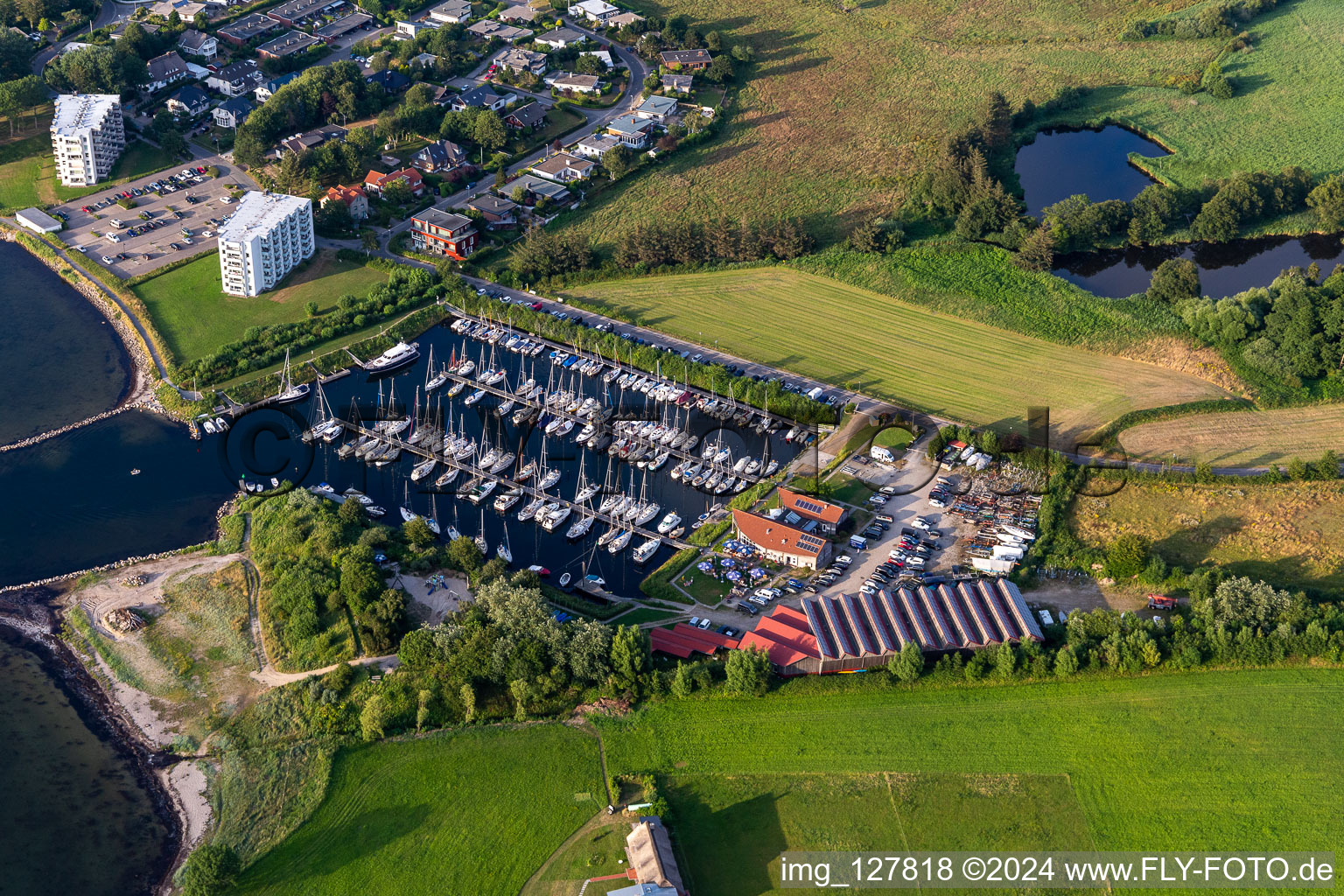 Aerial view of Pleasure boat marina of CLUB NAUTIC e.V. with docks and moorings on the shore area of the Foerde with Restaurant "Leuchtturm" in Schausende in Gluecksburg in the state Schleswig-Holstein, Germany