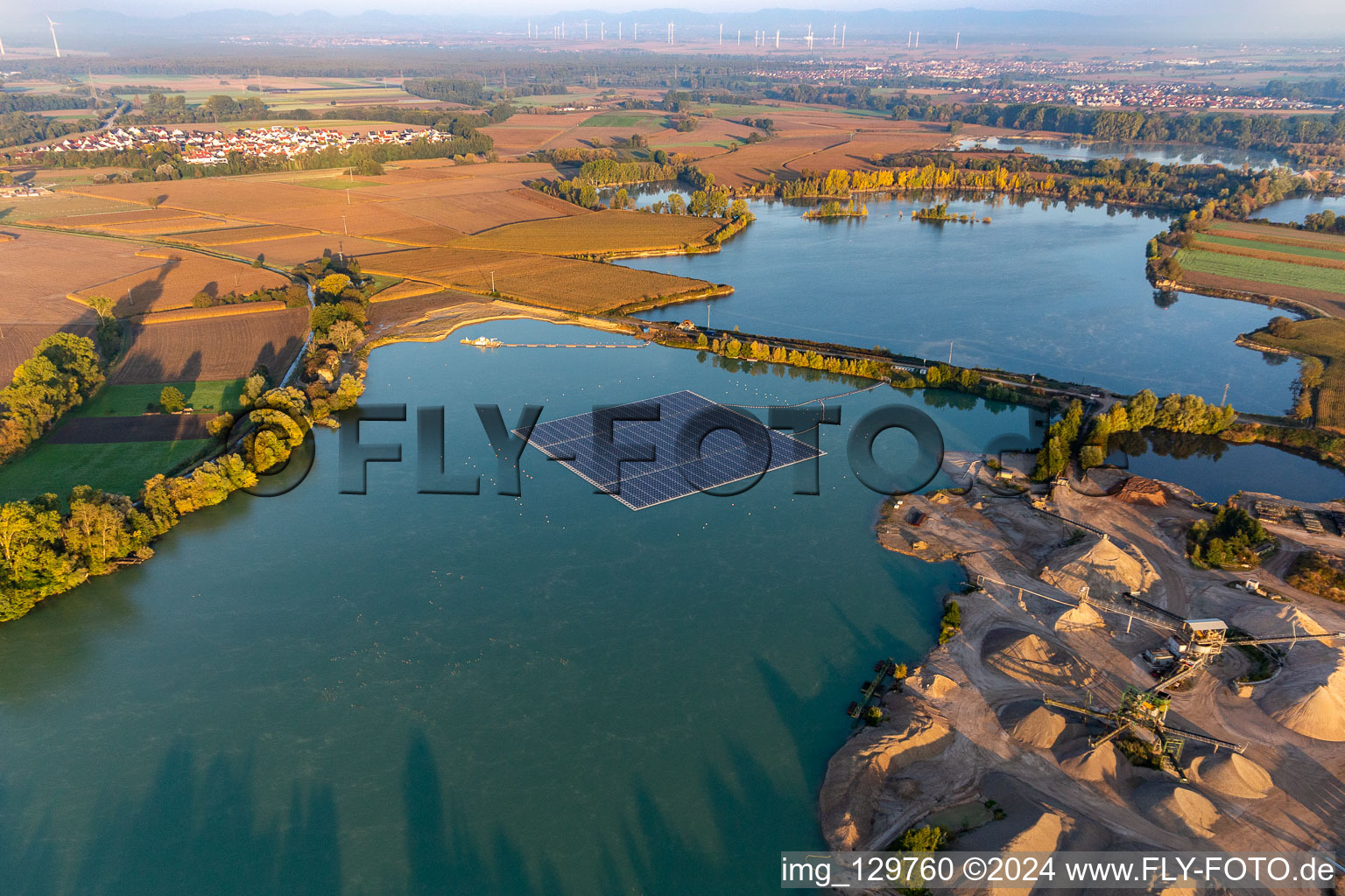 Floating solar power plant and panels of photovoltaic systems on the surface of the water on a quarry pond for gravel extraction in Leimersheim in the state Rhineland-Palatinate, Germany from above