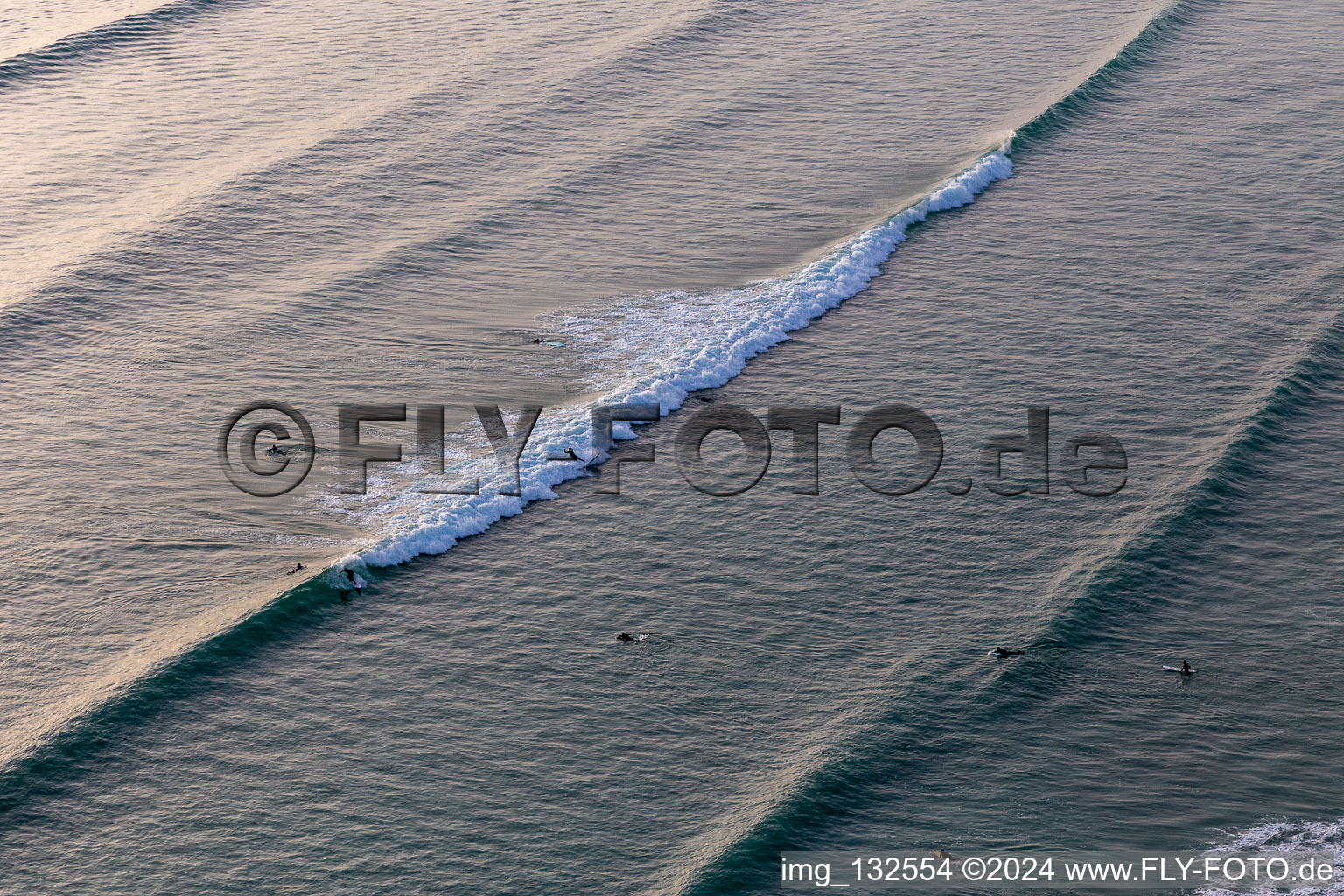 Aerial view of Wave surfers in front of the Plage de Tronoën in Saint-Jean-Trolimon in the state Finistere, France