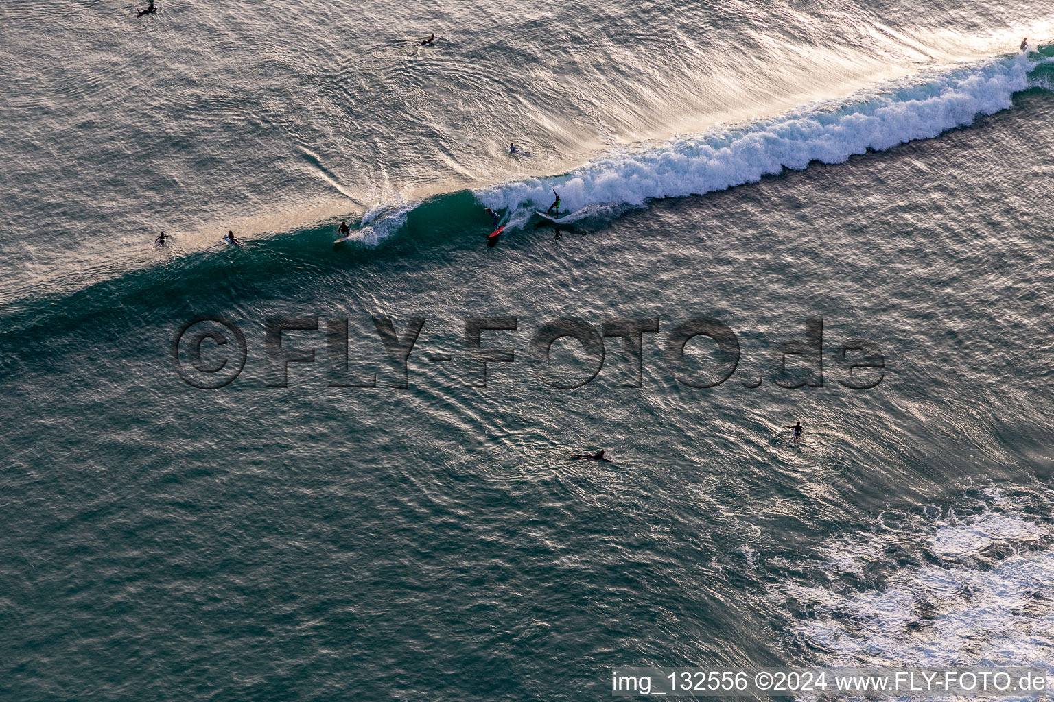 Oblique view of Wave surfers in front of the Plage de Tronoën in Saint-Jean-Trolimon in the state Finistere, France