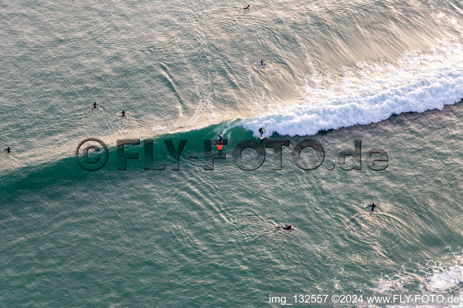 Wave surfers in front of the Plage de Tronoën in Saint-Jean-Trolimon in the state Finistere, France from above