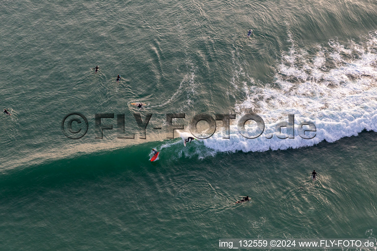 Wave surfers in front of the Plage de Tronoën in Saint-Jean-Trolimon in the state Finistere, France out of the air