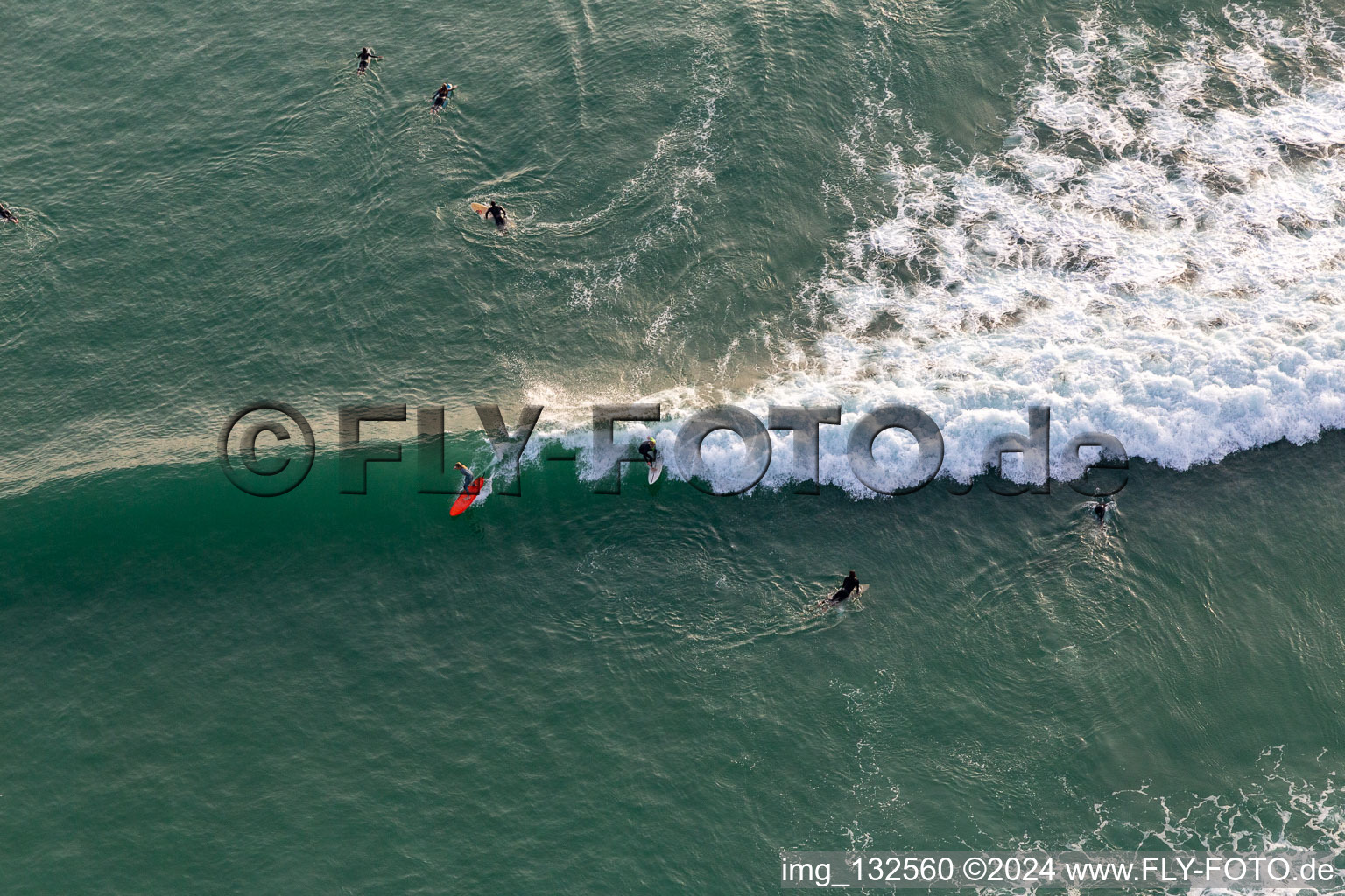 Wave surfers in front of the Plage de Tronoën in Saint-Jean-Trolimon in the state Finistere, France seen from above