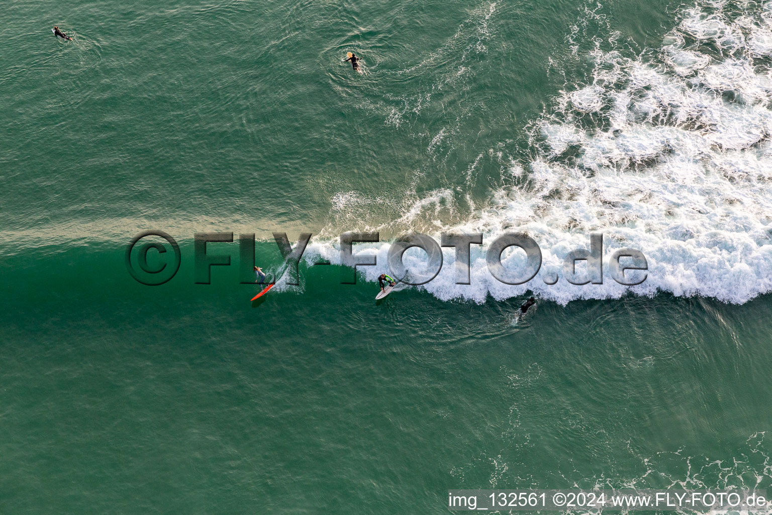 Wave surfers in front of the Plage de Tronoën in Saint-Jean-Trolimon in the state Finistere, France from the plane