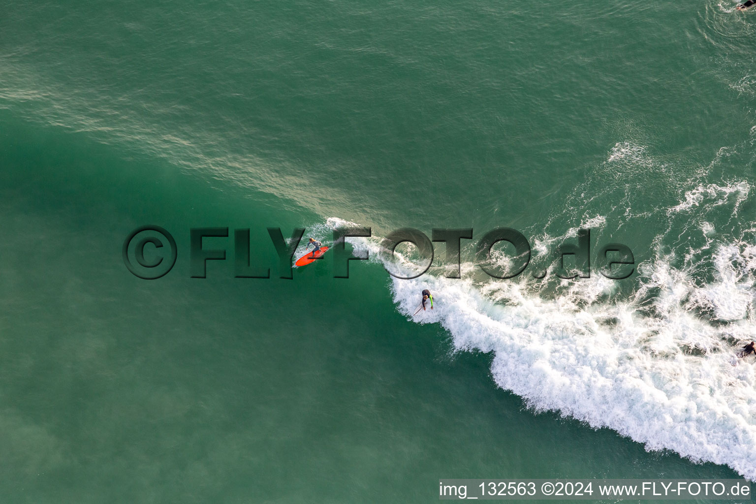 Wave surfers in front of the Plage de Tronoën in Saint-Jean-Trolimon in the state Finistere, France viewn from the air