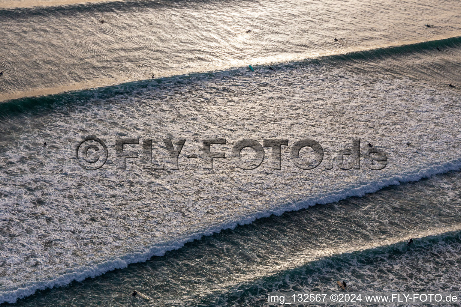 Wave surfers in front of the Plage de Tronoën in Saint-Jean-Trolimon in the state Finistere, France from the drone perspective