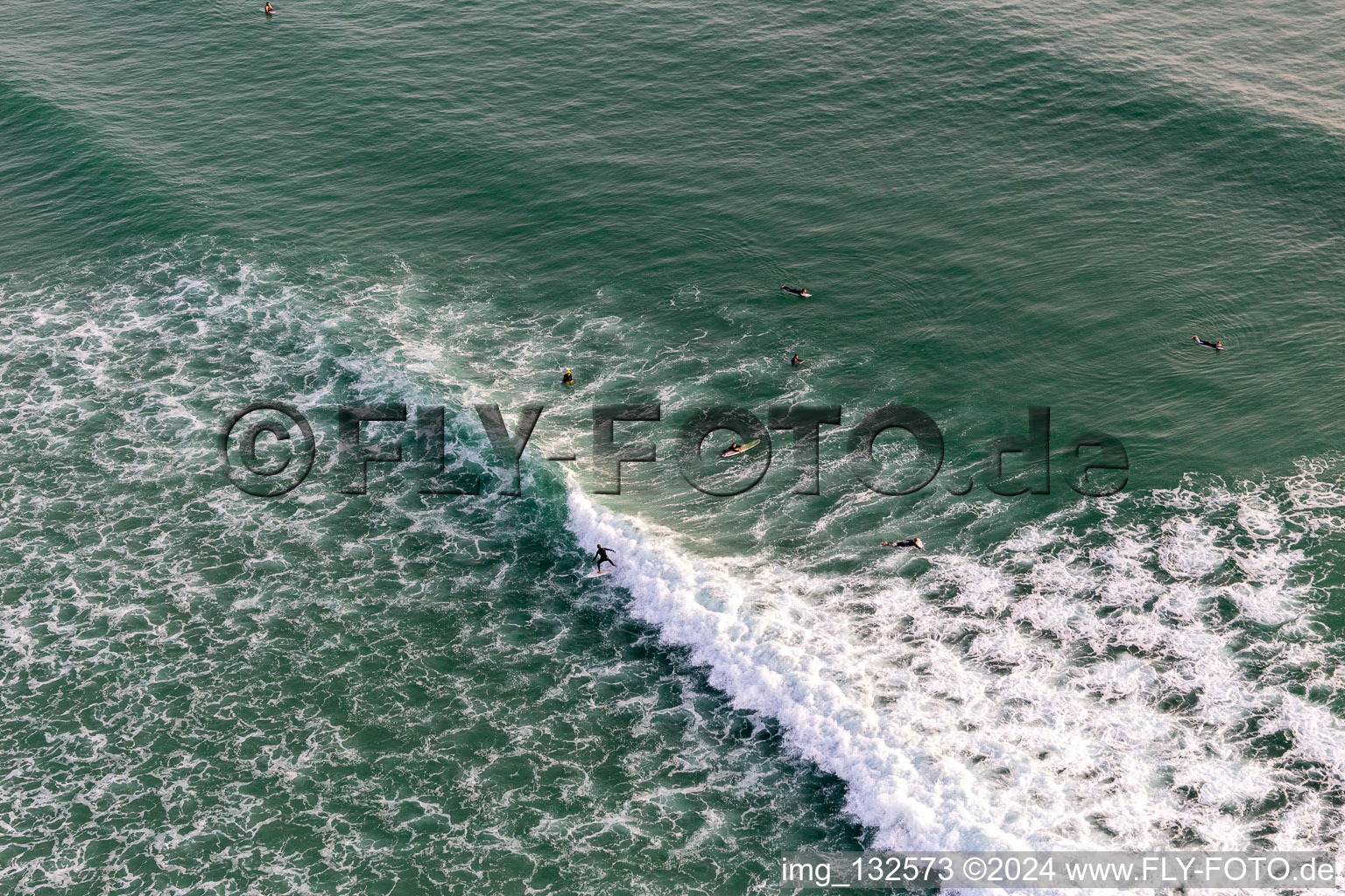 Aerial view of Wave surfers in front of the Plage de Tronoën in Saint-Jean-Trolimon in the state Finistere, France