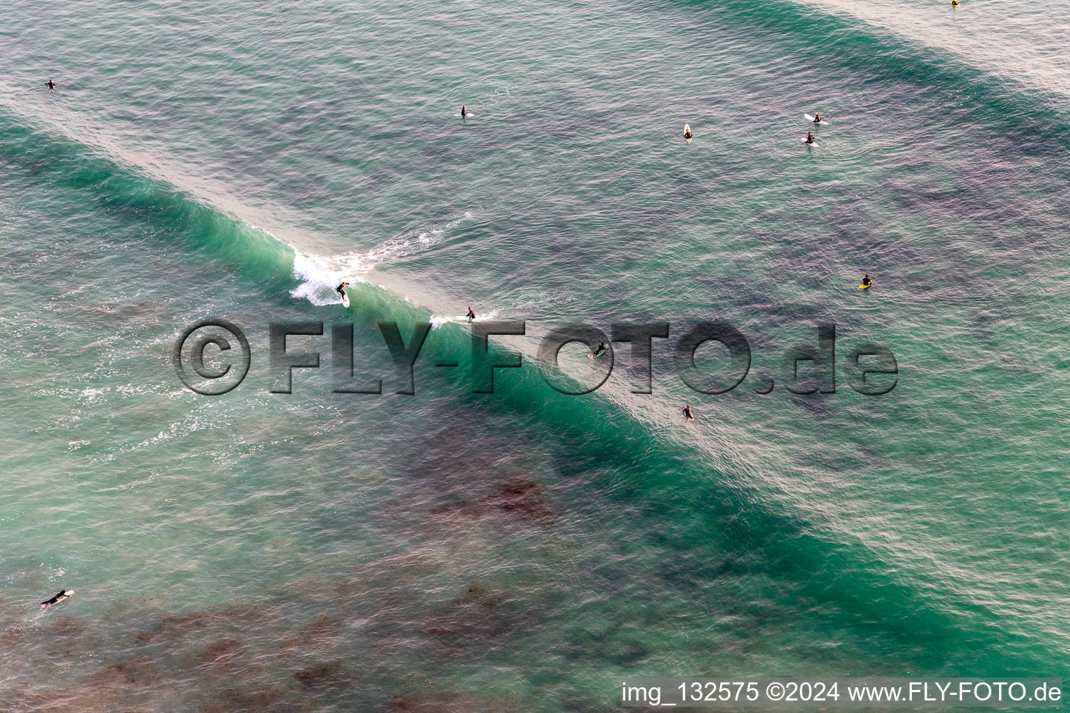 Aerial view of Wave surfers in front of Plage la Torche-Tronoën in Saint-Jean-Trolimon in the state Finistere, France