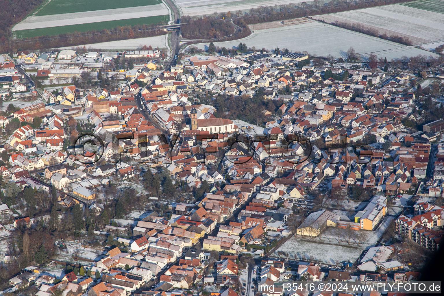 Main street with parish church of St. Michael in winter with snow in Rheinzabern in the state Rhineland-Palatinate, Germany