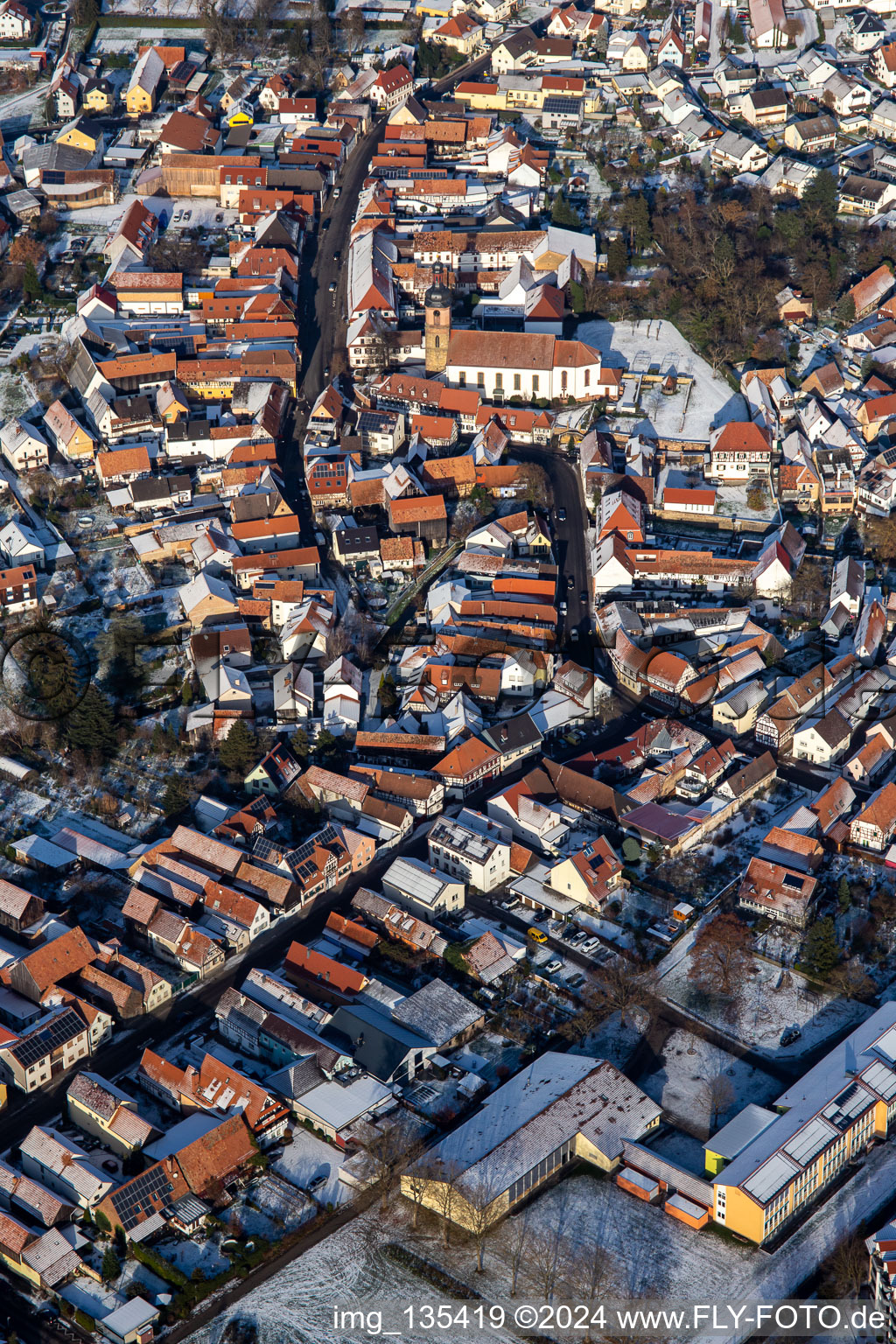 Oblique view of Main street with parish church of St. Michael in winter with snow in Rheinzabern in the state Rhineland-Palatinate, Germany