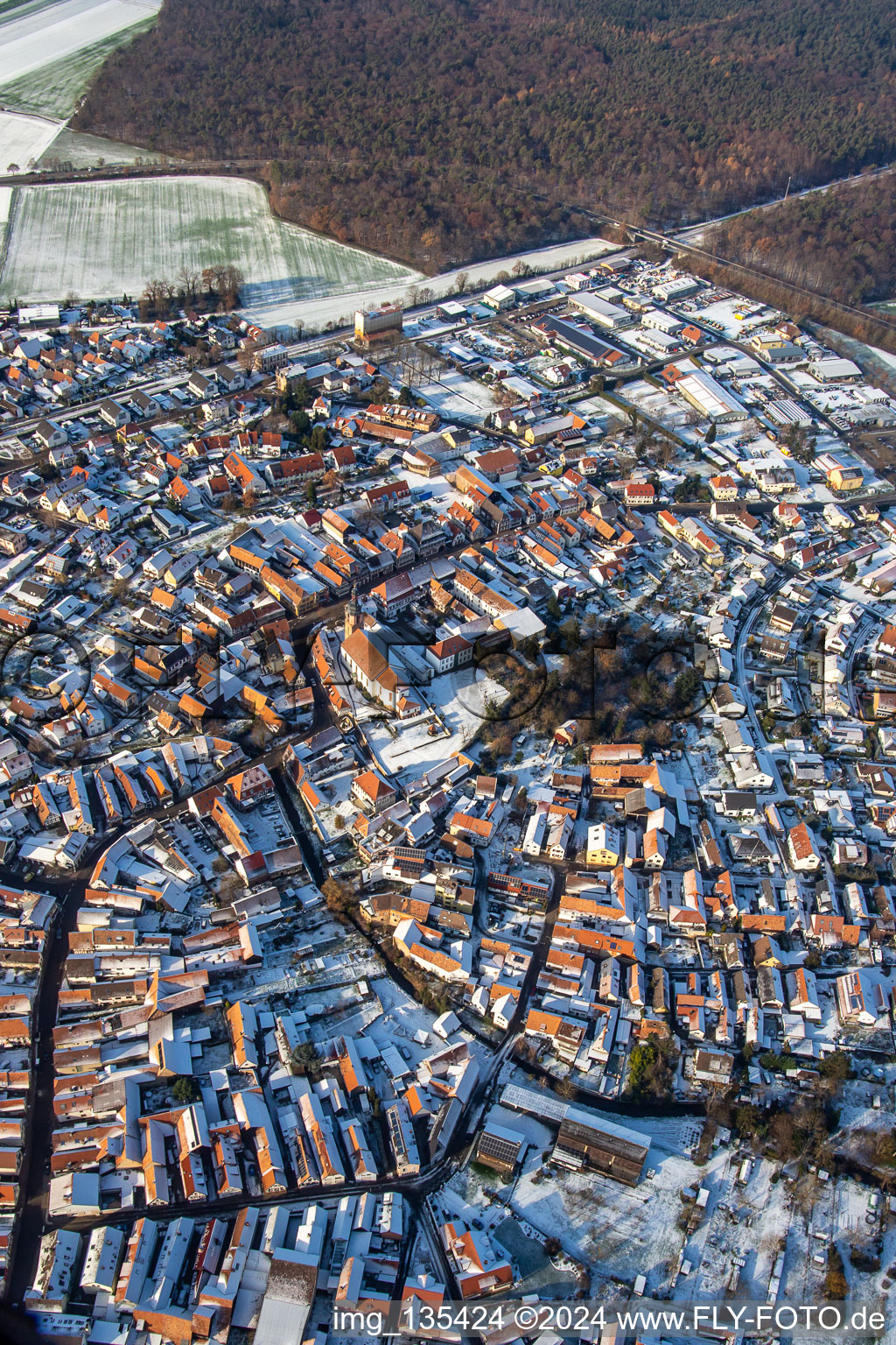 Main street with parish church of St. Michael in winter with snow in Rheinzabern in the state Rhineland-Palatinate, Germany from the plane