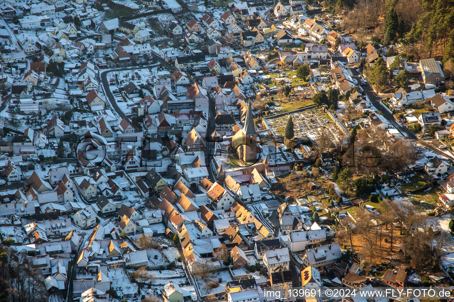 Fortified church of St. Martin and cemetery in winter with snow in Dörrenbach in the state Rhineland-Palatinate, Germany