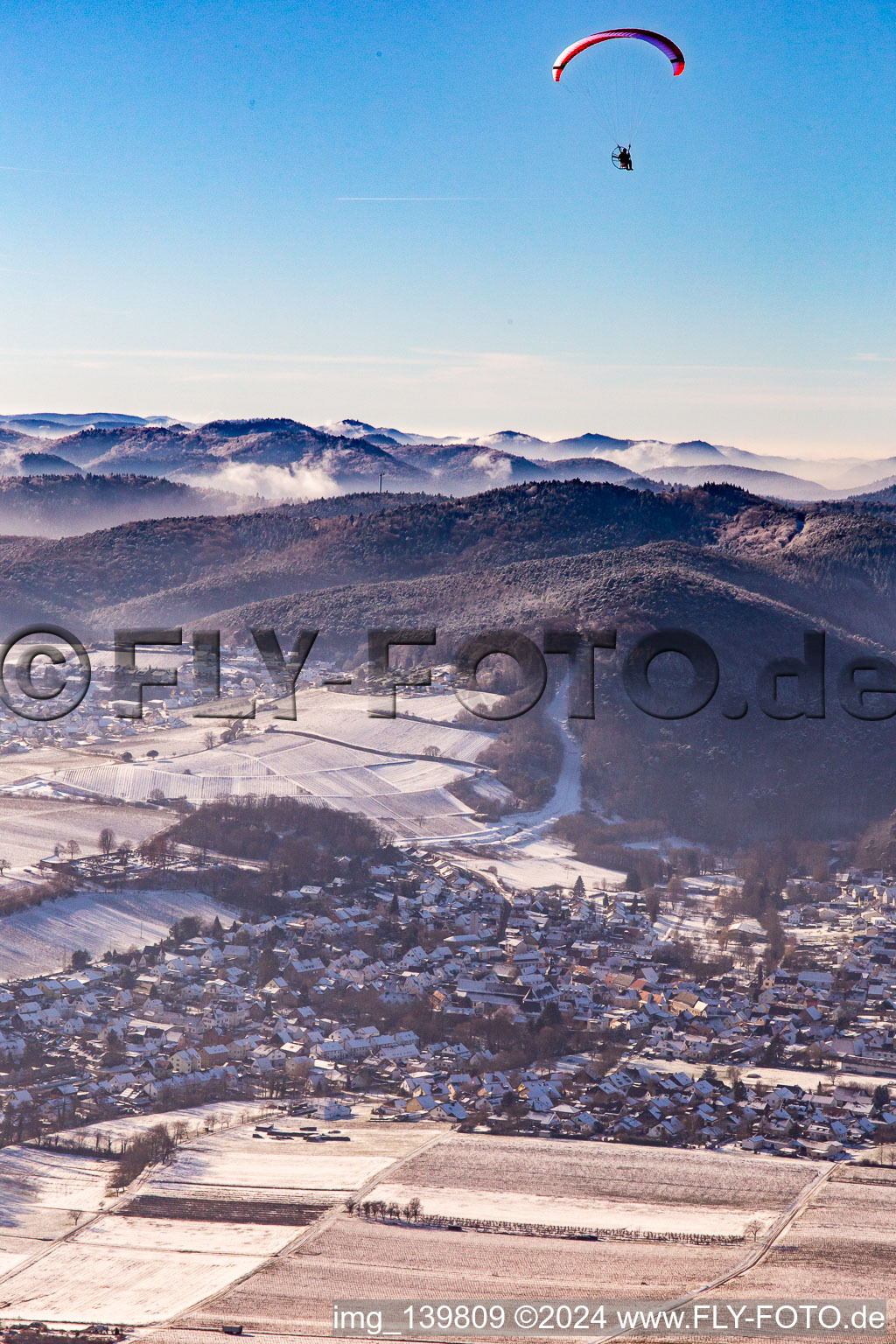 From the east in winter in the snow with paraglider in Klingenmünster in the state Rhineland-Palatinate, Germany