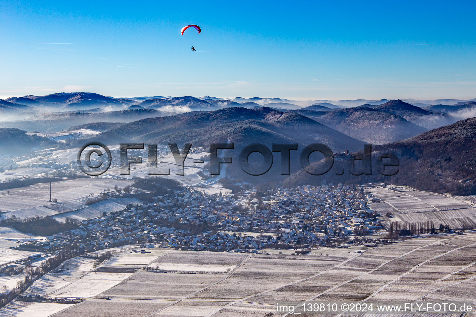 Aerial view of From the east in winter in the snow with a paraglider in Klingenmünster in the state Rhineland-Palatinate, Germany