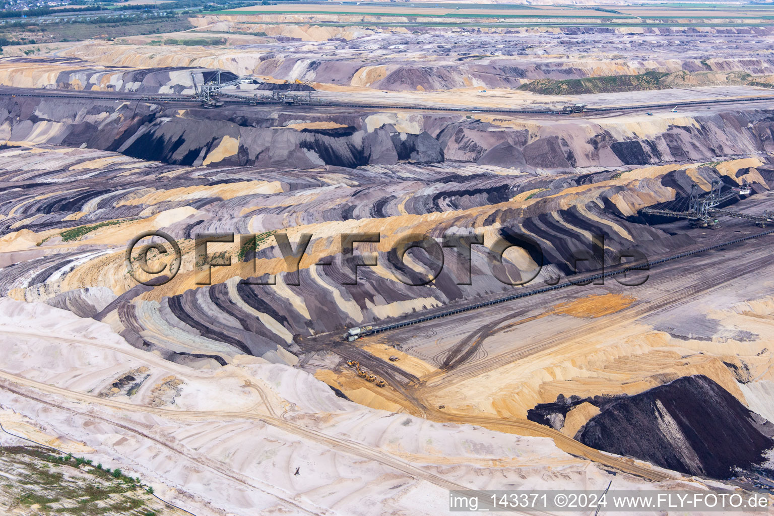 Interestingly colored layers of overburden and coal in the Garzweiler opencast lignite mine in the district Borschemich in Erkelenz in the state North Rhine-Westphalia, Germany from the plane