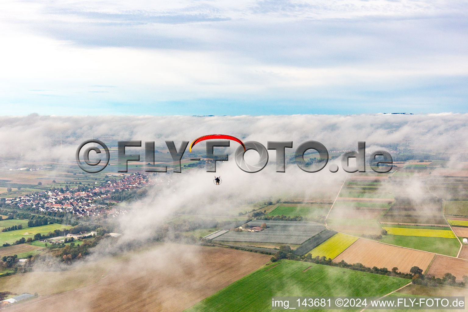 Village with paraglider under autumn clouds in Winden in the state Rhineland-Palatinate, Germany
