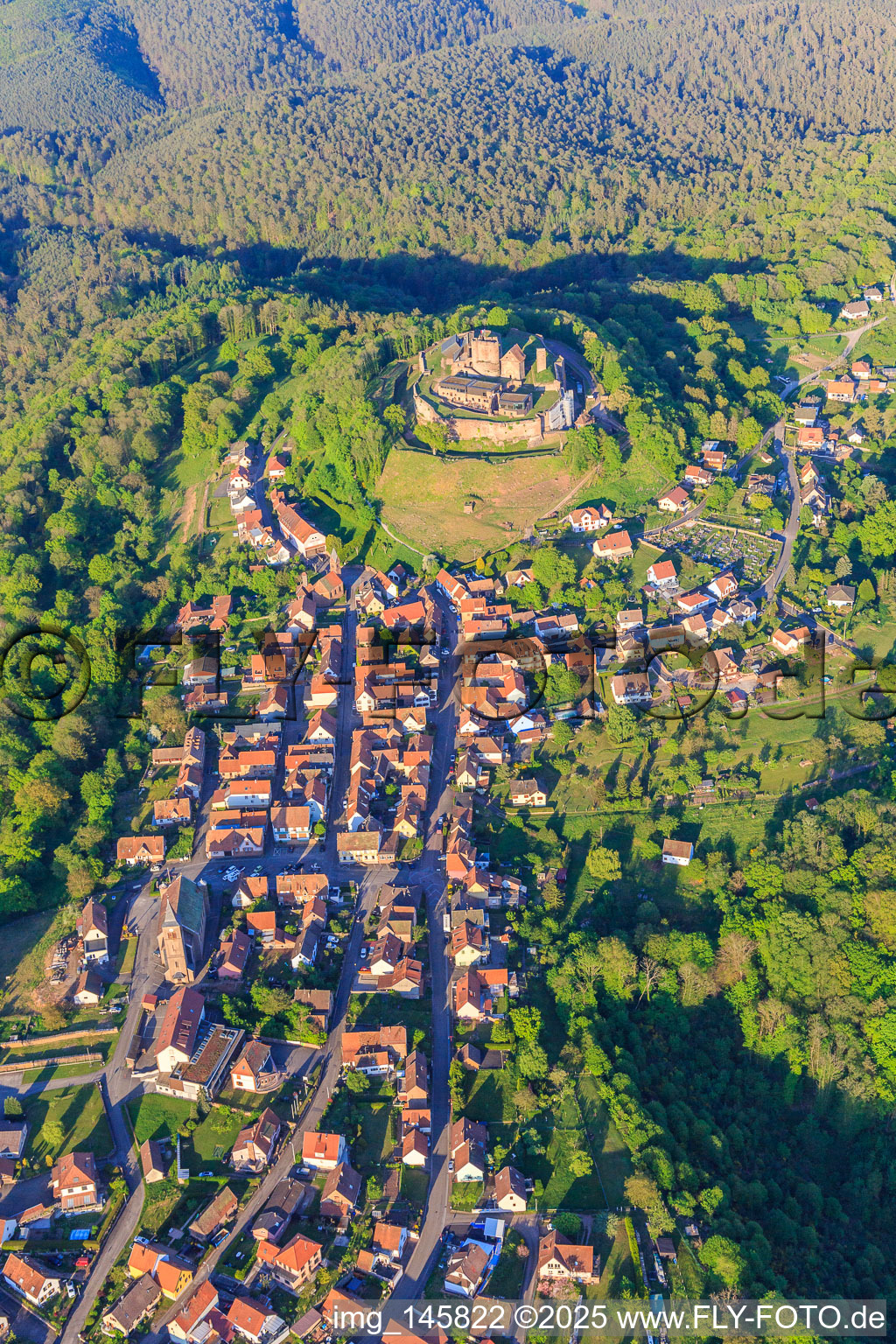 View of the village in the Northern Vosges from the west with the church of Notre-Dame-Marie-Auxilliatrice below the Château de Lichtenberg in Lichtenberg in the state Bas-Rhin, France