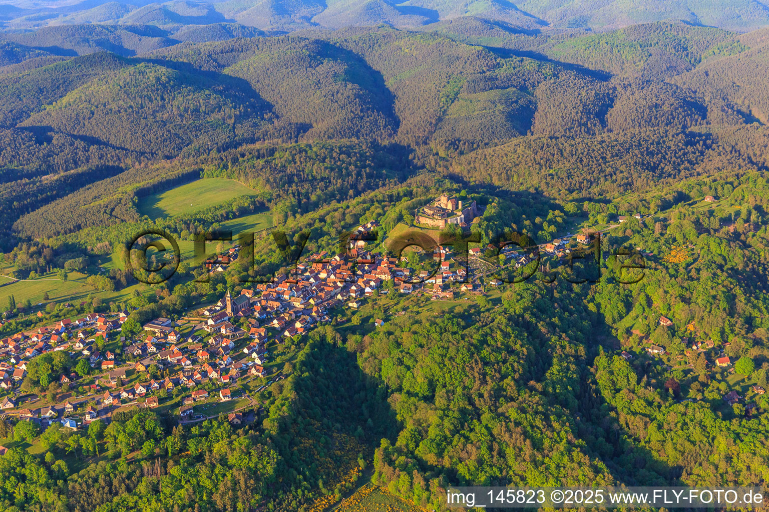 View of the village in the Northern Vosges from the southwest with the church of Notre-Dame-Marie-Auxilliatrice below the Château de Lichtenberg in Lichtenberg in the state Bas-Rhin, France