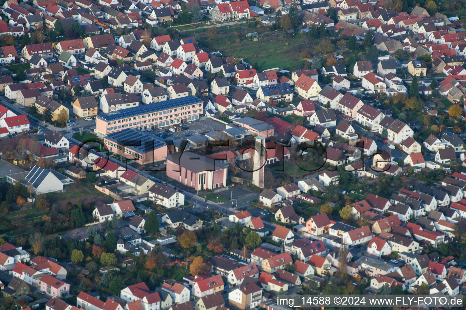 School building of the Ernst-Reuter school and Tower and building of St. Ulrich church in Hassloch in the state Rhineland-Palatinate