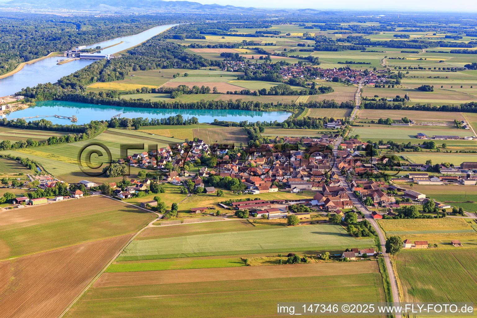 Village view from the north in front of the quarry lake/gravel works of Les Gravières Rhénanes SAS in Friesenheim in the state Bas-Rhin, France