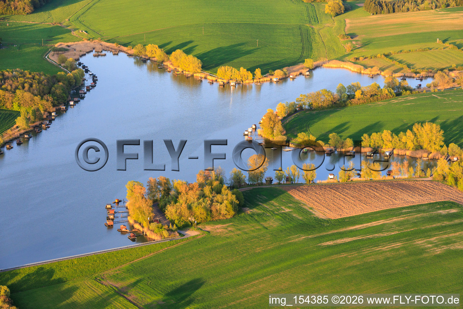 Boardwalks with fishing huts line the shore of Lake Etang du Welschhof. in Puttelange-aux-Lacs in the state Moselle, France