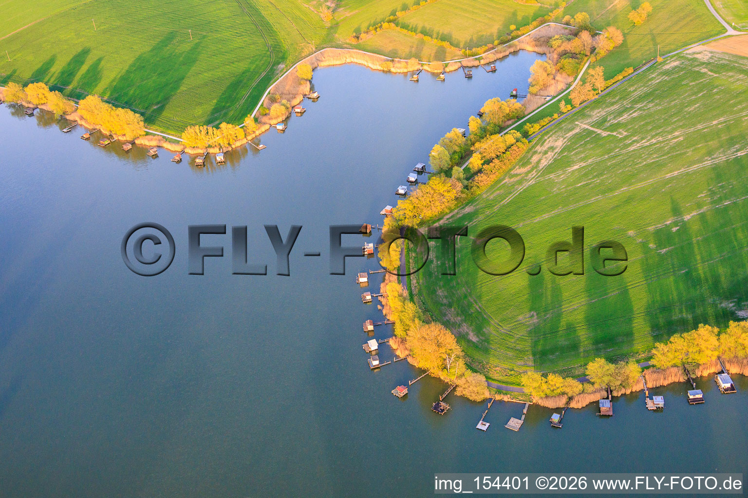 Boardwalks with fishing huts line the shore of Lake Etang du Welschhof. in Puttelange-aux-Lacs in the state Moselle, France