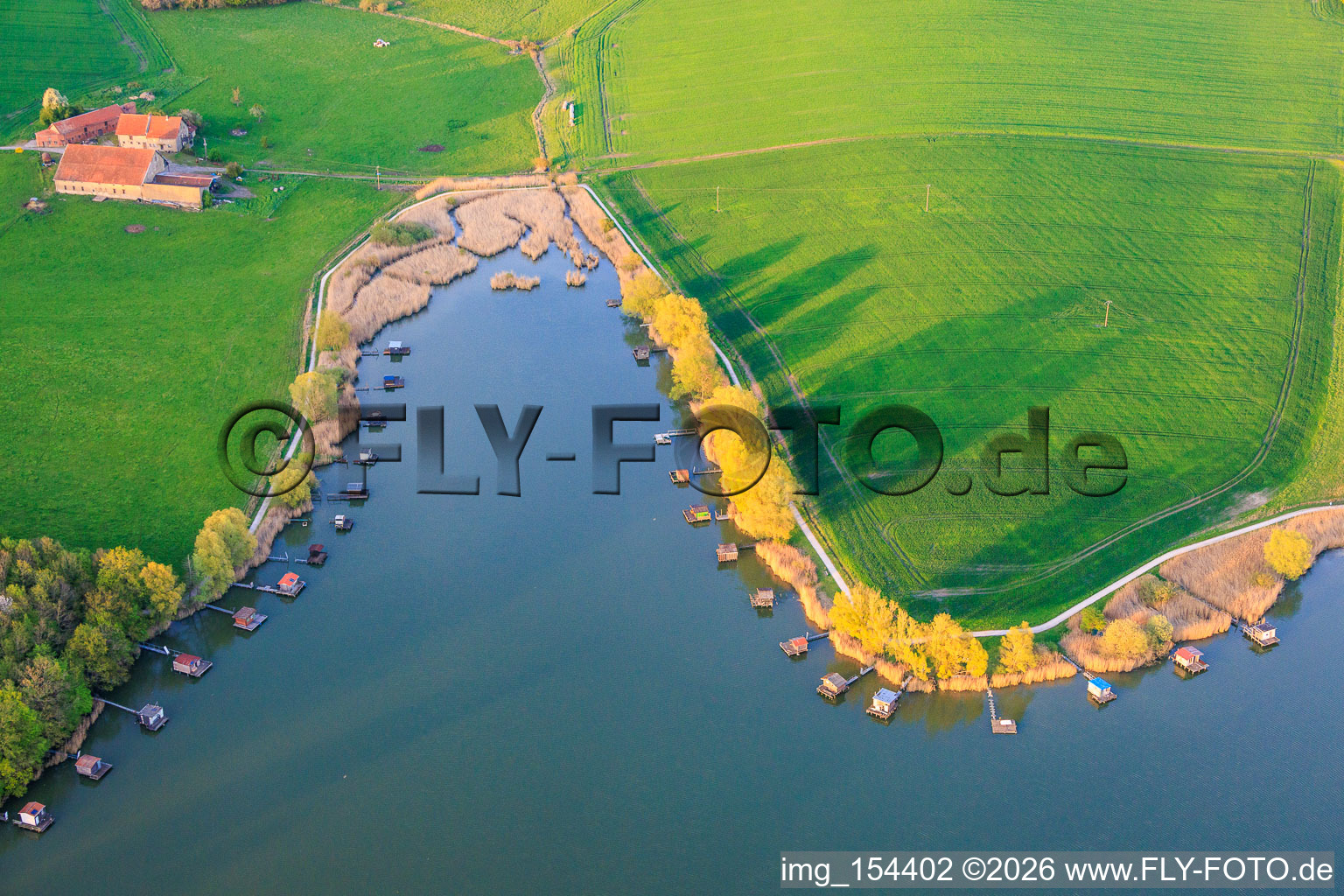 Boardwalks with fishing huts line the shore of Lake Etang du Welschhof. in Puttelange-aux-Lacs in the state Moselle, France