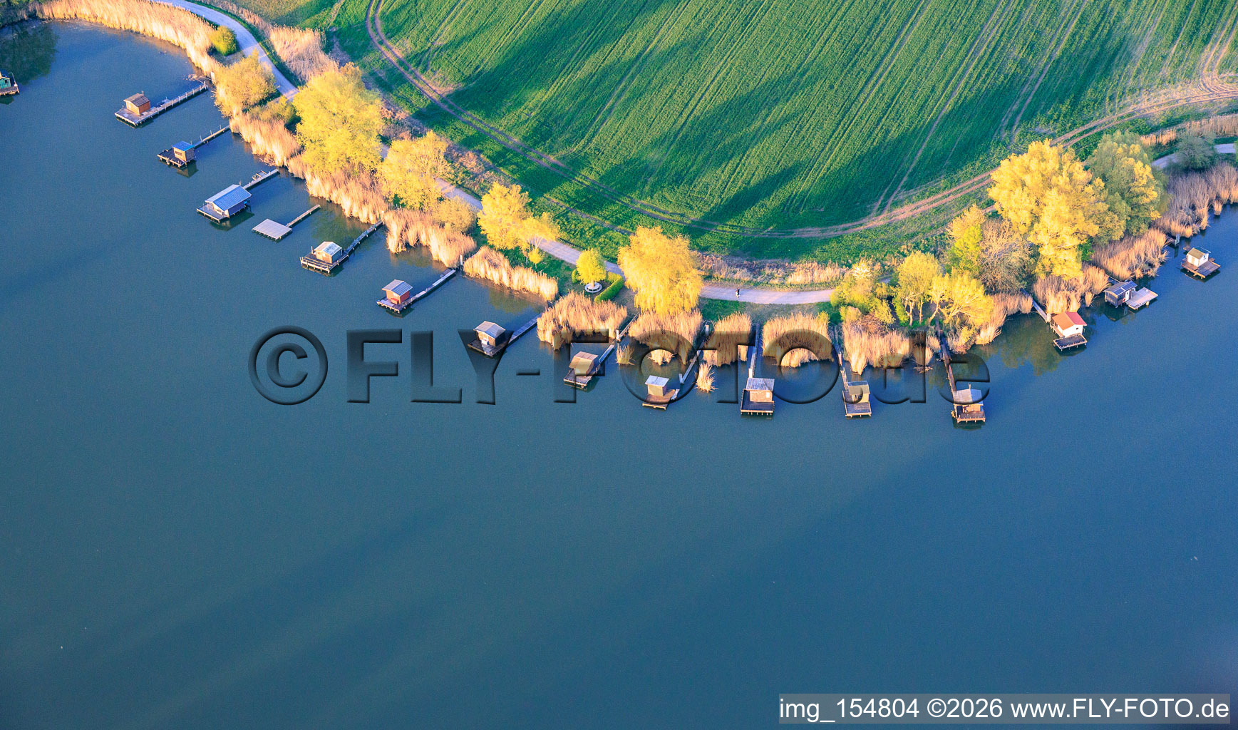 Boardwalks with fishing huts line the shore of Lake Etang du Welschhof. in Puttelange-aux-Lacs in the state Moselle, France