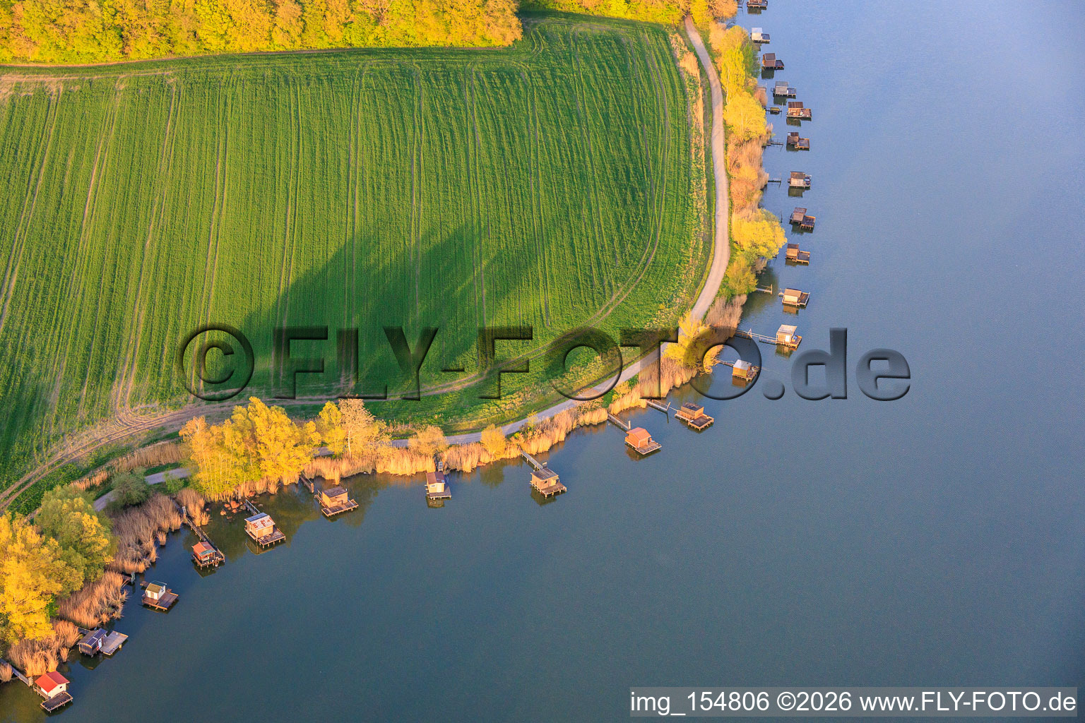 Boardwalks with fishing huts line the shore of Lake Etang du Welschhof. in Puttelange-aux-Lacs in the state Moselle, France