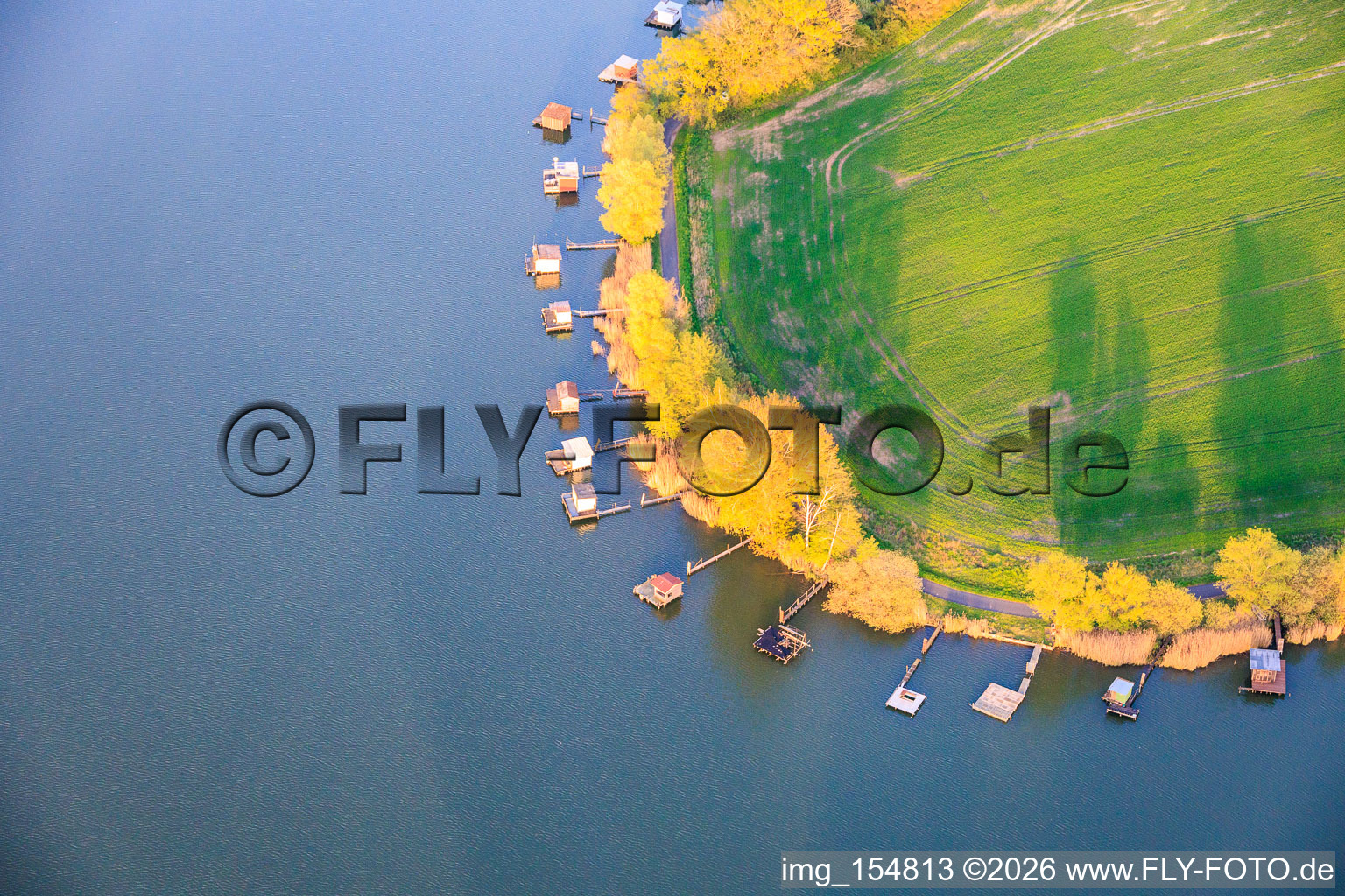 Boardwalks with fishing huts line the shore of Lake Etang du Welschhof. in Puttelange-aux-Lacs in the state Moselle, France