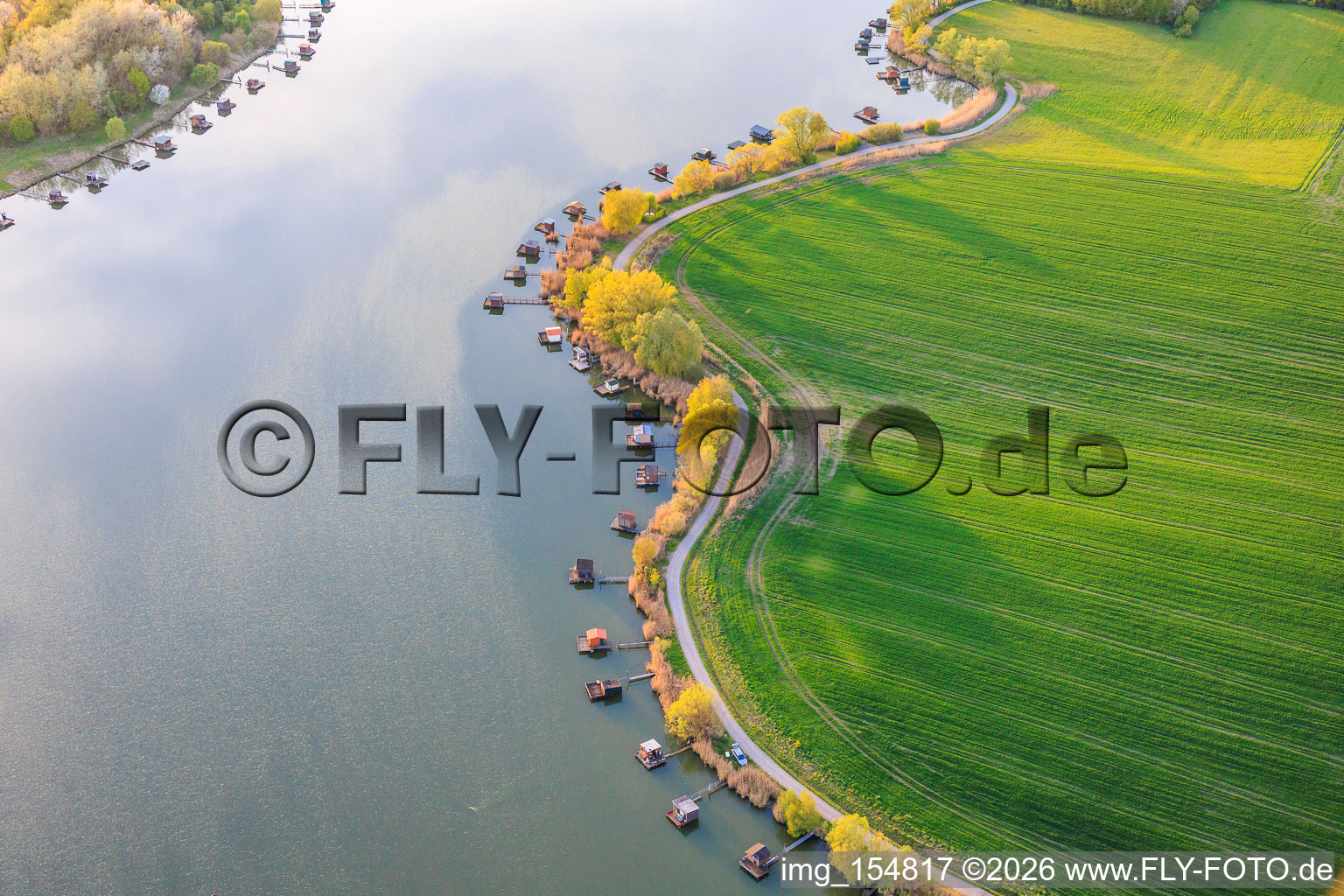 Boardwalks with fishing huts line the shore of Lake Etang du Welschhof. in Puttelange-aux-Lacs in the state Moselle, France